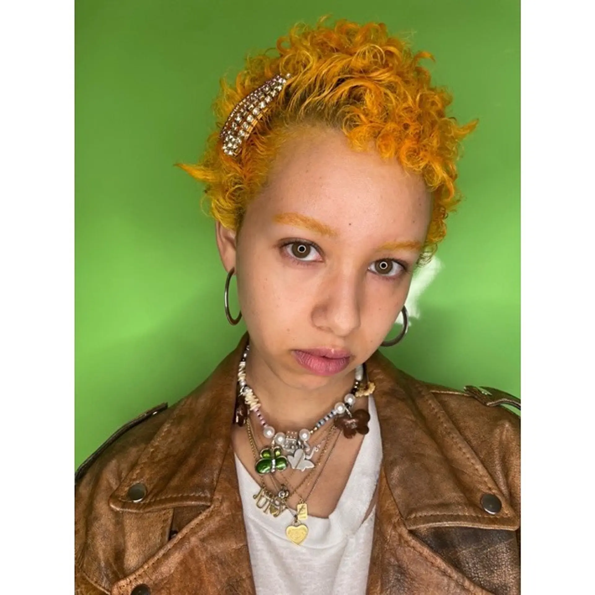 A short, textured curly cut with a vibrant tangerine color. 1