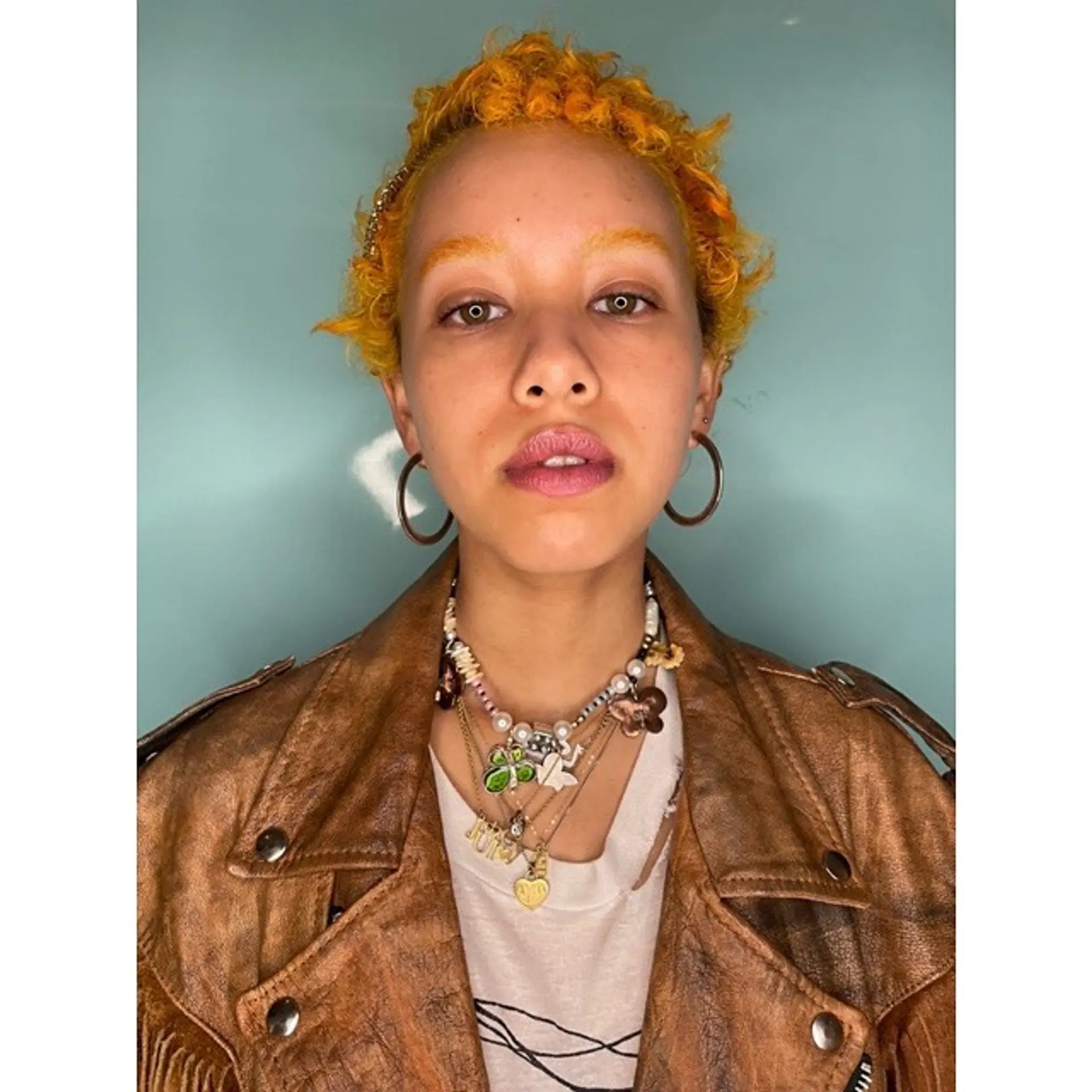 A short, textured curly cut with a vibrant tangerine color. 2