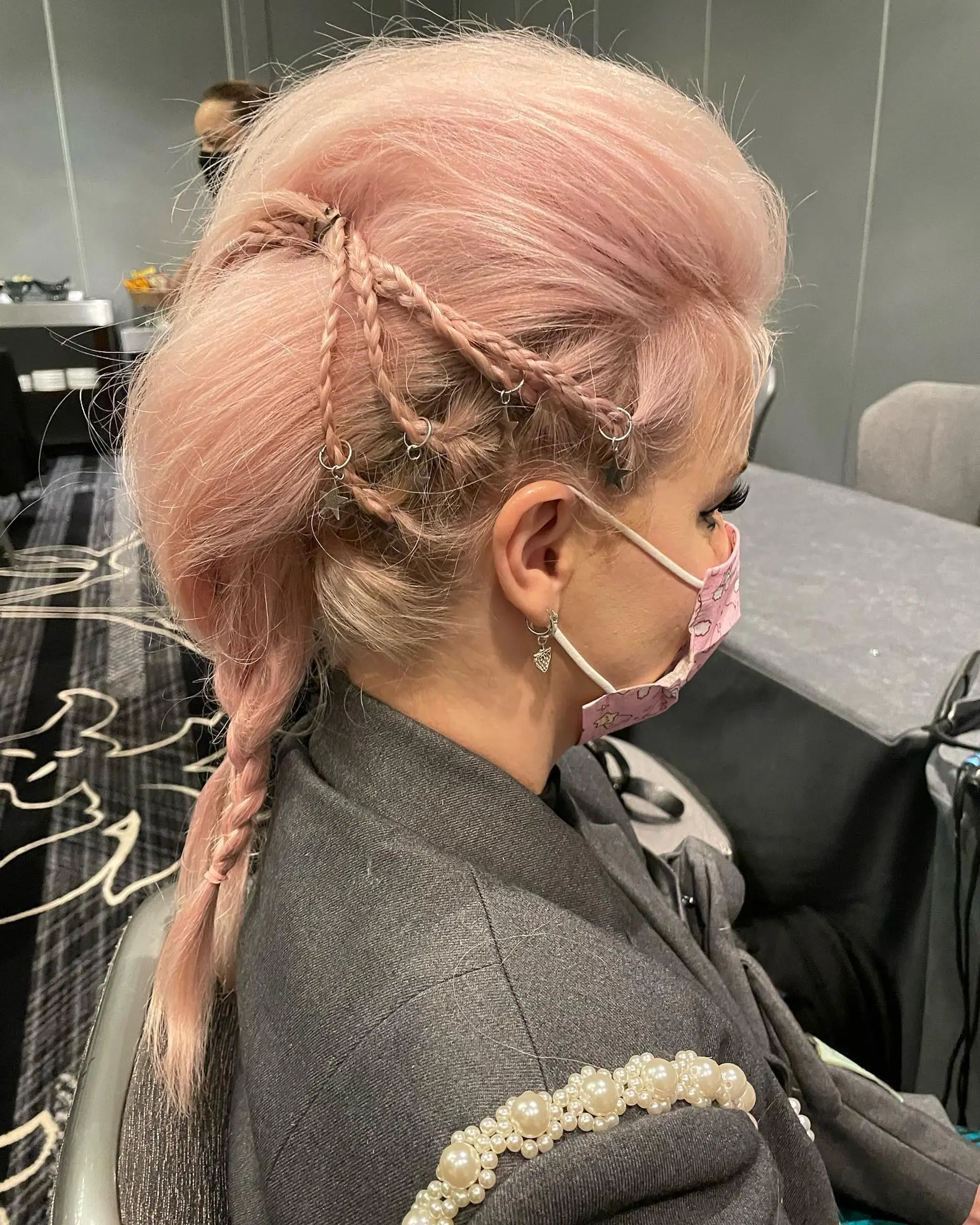 A voluminous pastel pink faux hawk styled with intricate side braids accented with silver piercing rings and star charms. 1