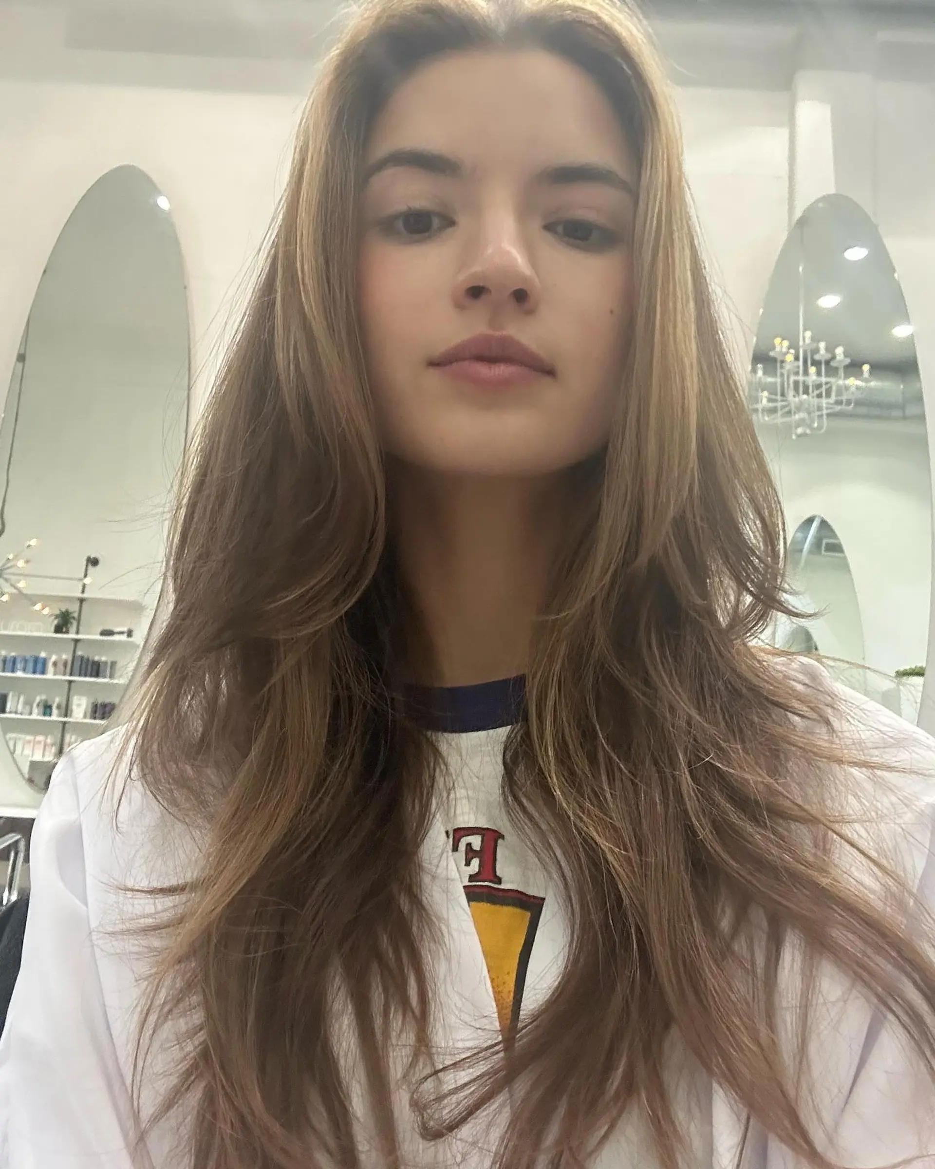 Long layered haircut featuring soft face-framing pieces and subtle sun-kissed highlights. 1