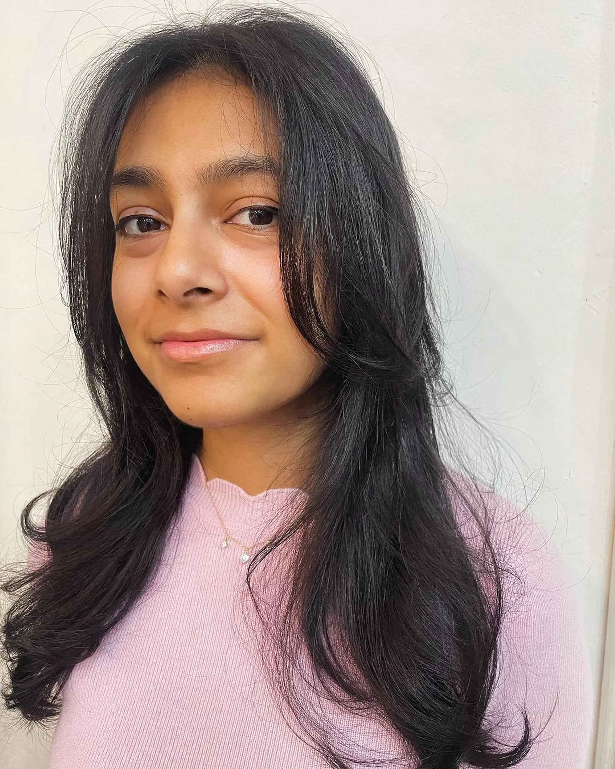 A sophisticated long, wavy black hairstyle with meticulous layers and a gentle side part, enhancing natural volume and movement.