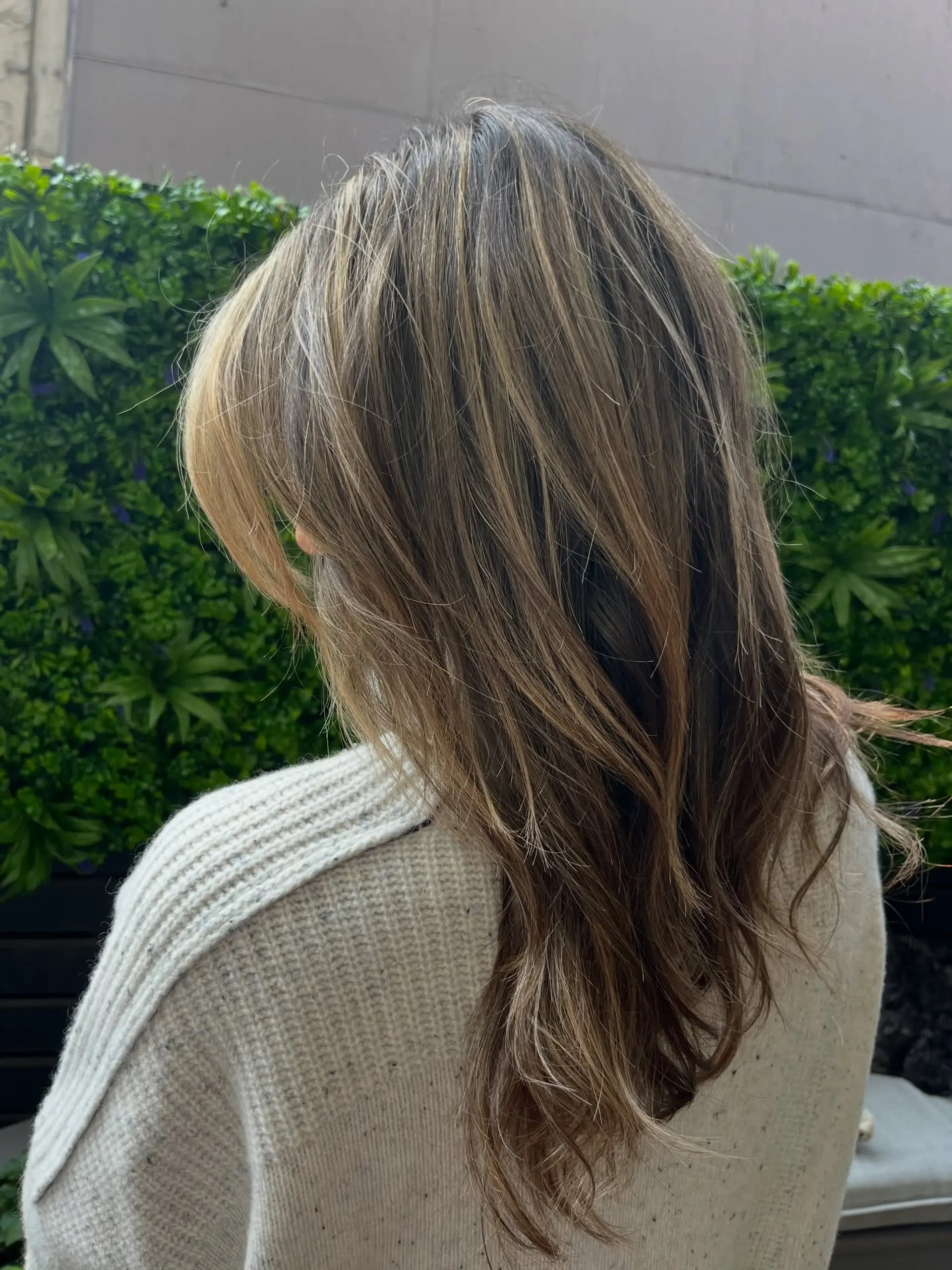 Long dimensional brunette hair layered with warm honey and caramel balayage highlights, styled with gentle movement. 1