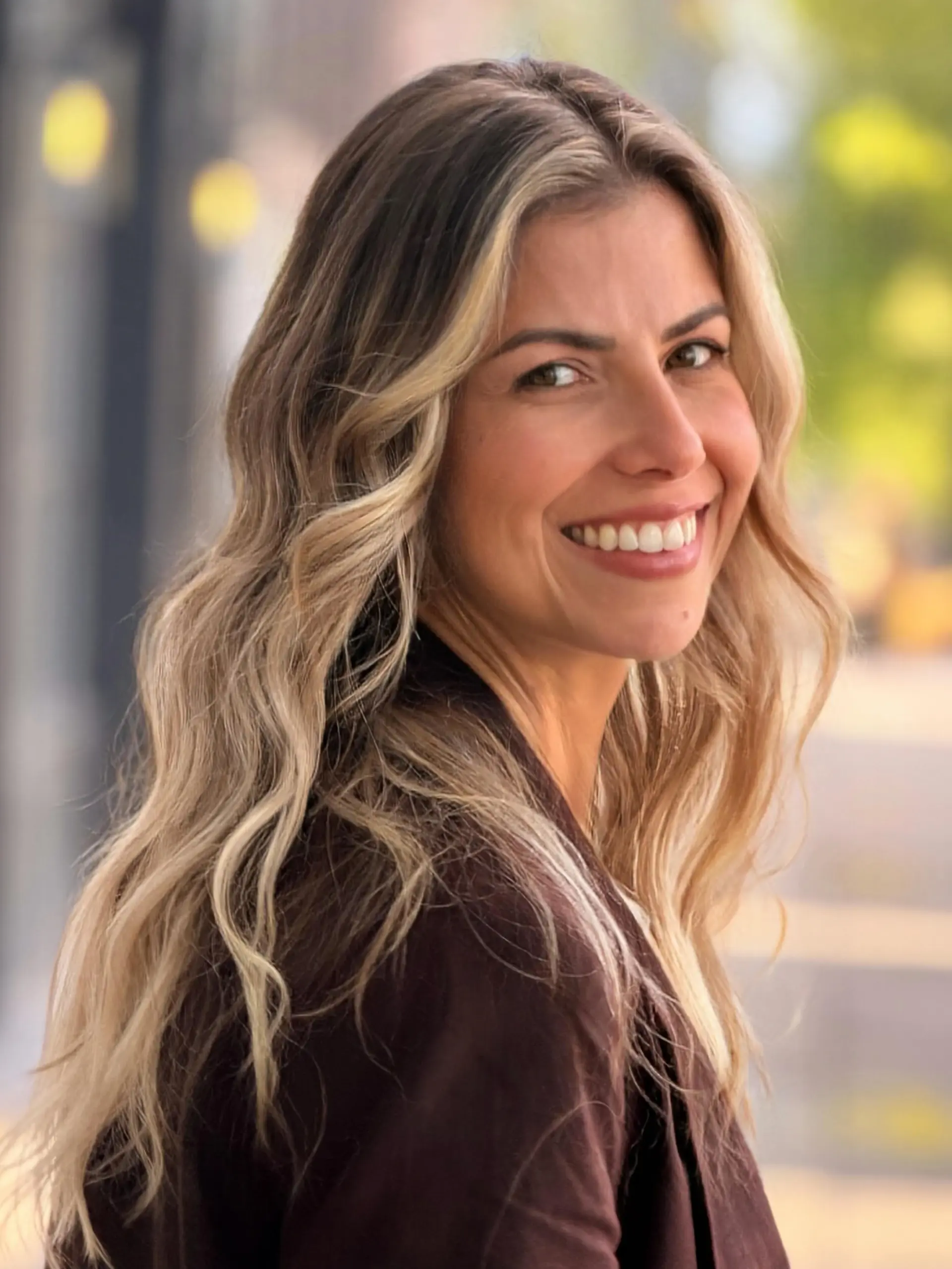 Long wavy hair with a warm blonde balayage and bright face-framing highlights over a light brunette base. 1