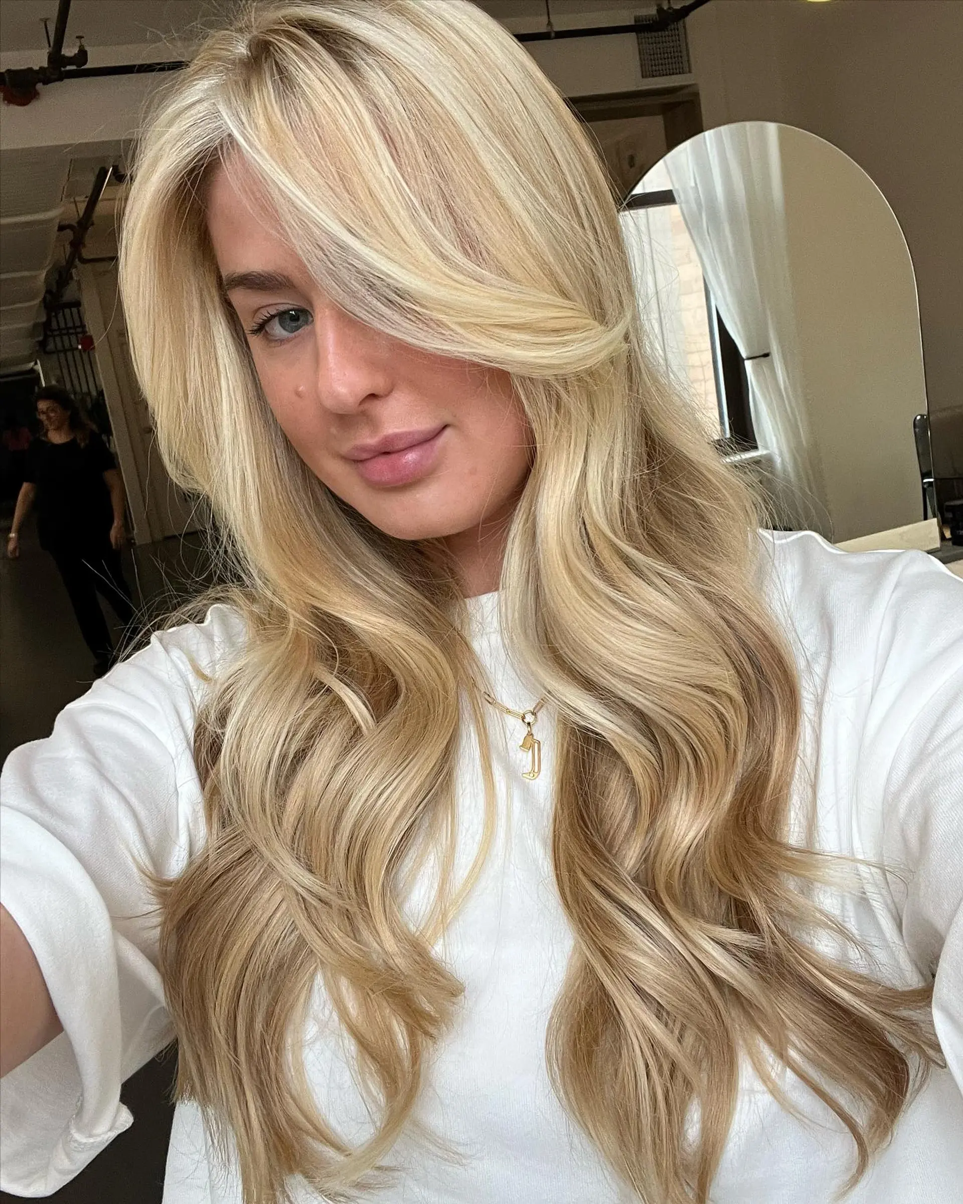 Long, flowing blonde balayage styled into voluminous, loose soft waves with a sweeping face-framing fringe. 1