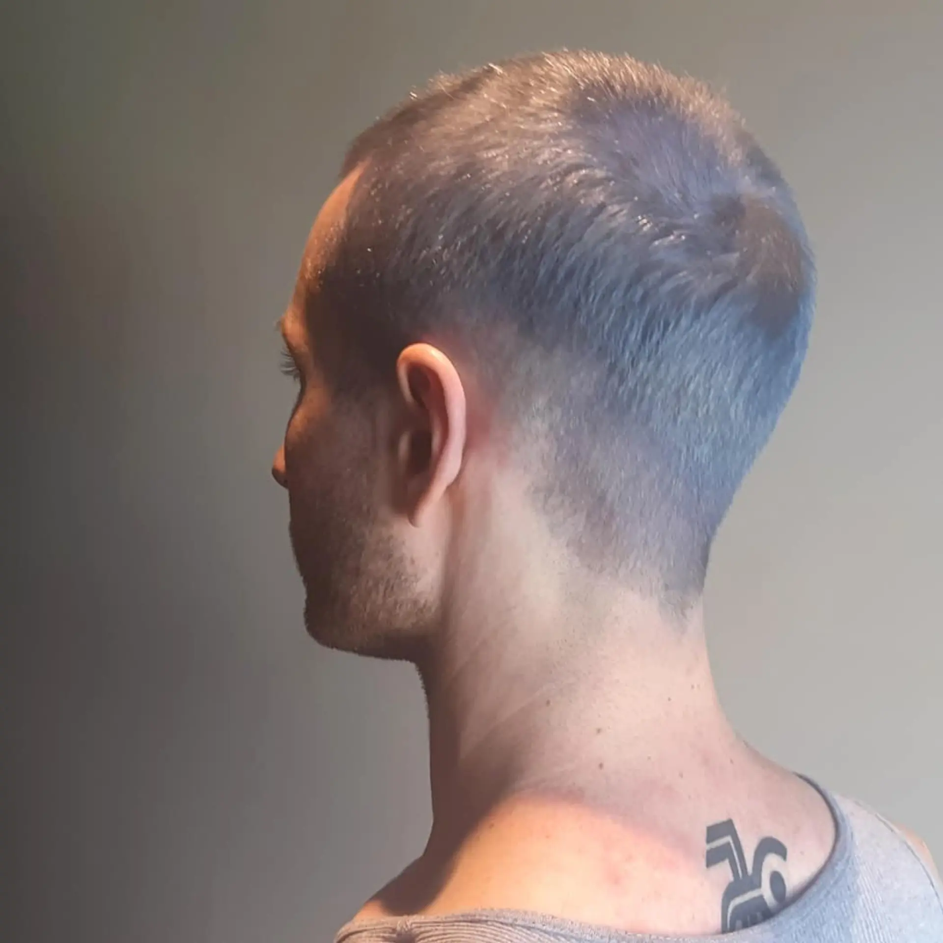 A very short buzz cut with a faded taper around the sides and back. 1