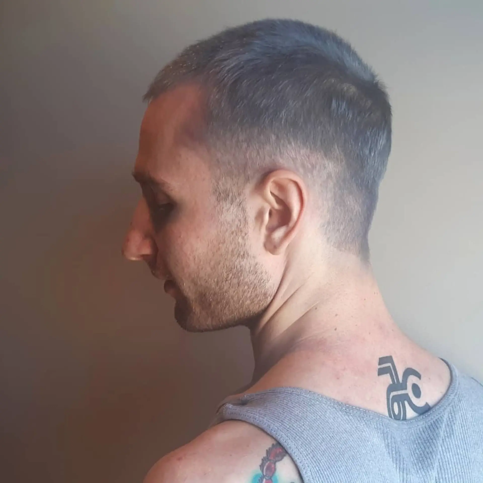 A very short buzz cut with a faded taper around the sides and back. 2
