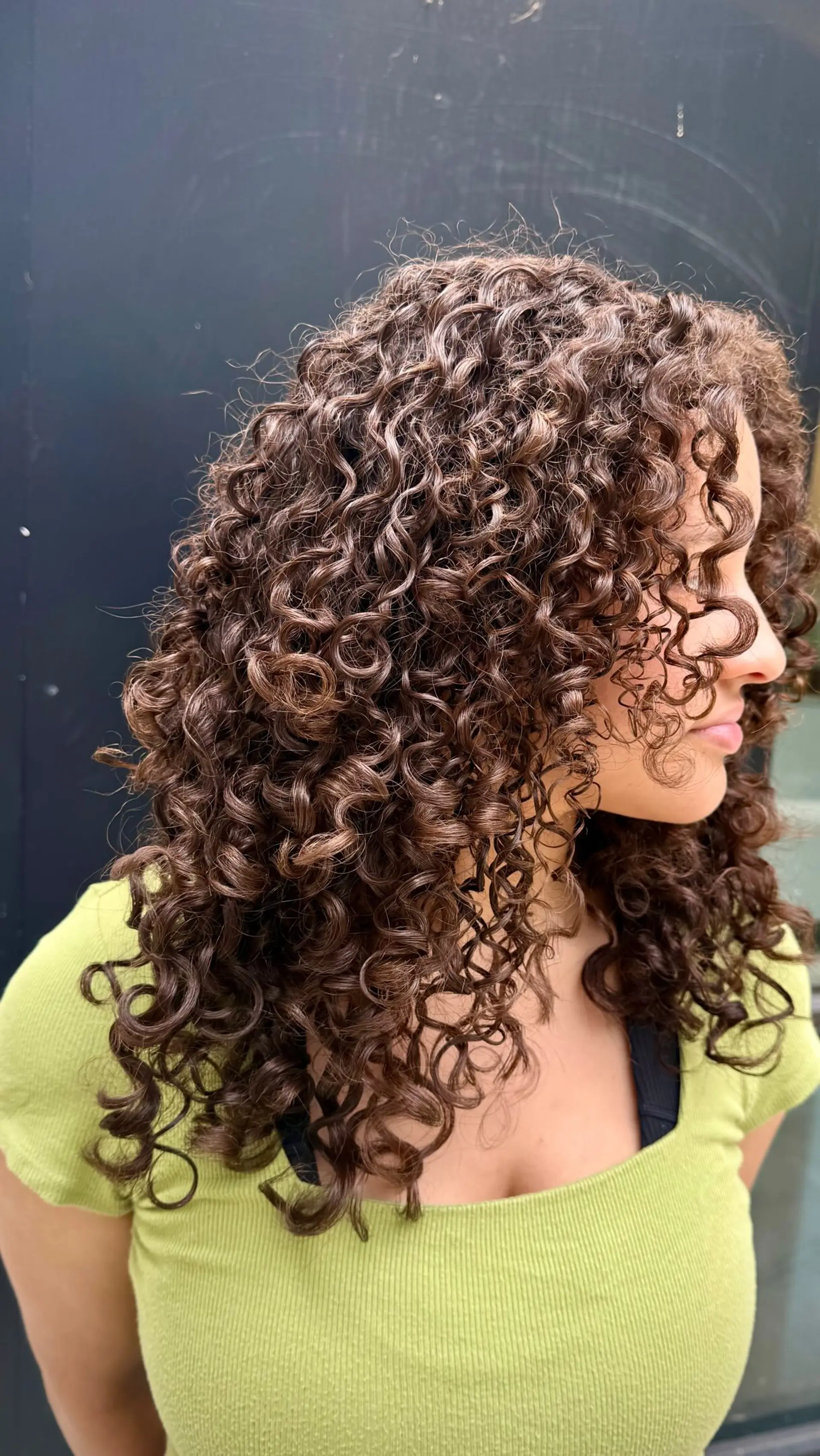 Defined medium-length brown curls styled with rounded layers and face-framing tendrils. 1