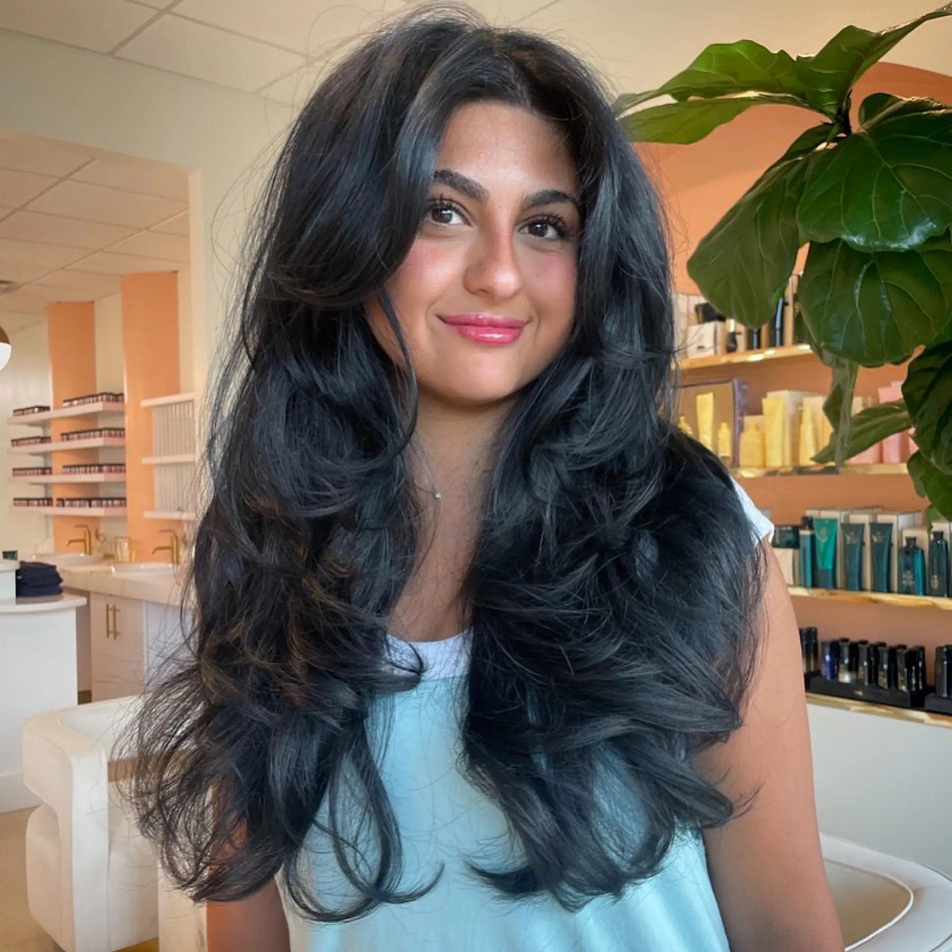 Voluminous long black layered haircut styled in a bouncy blowout with face-framing curtain layers. 1