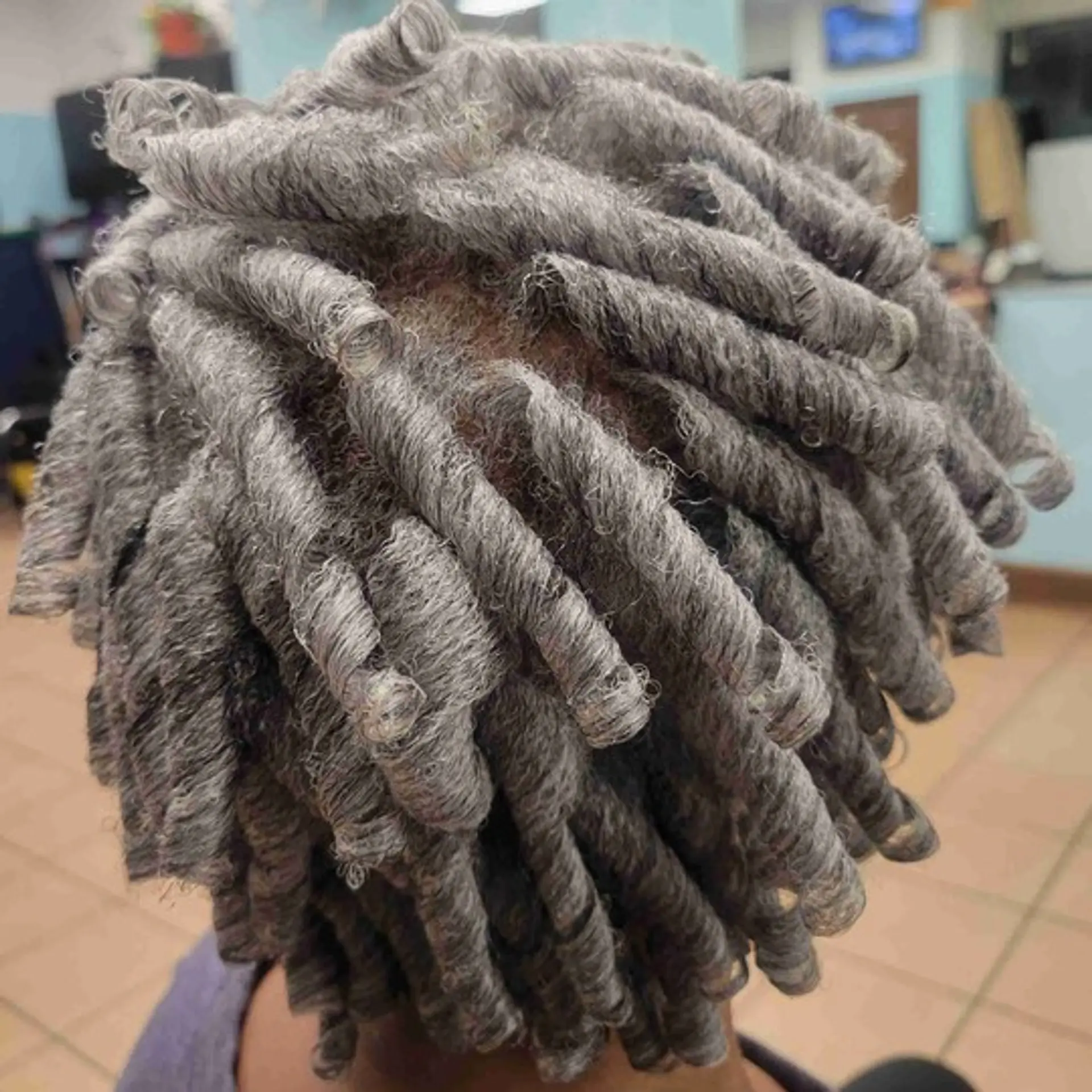 A short, coiled loc hairstyle featuring defined and textured coils. 1