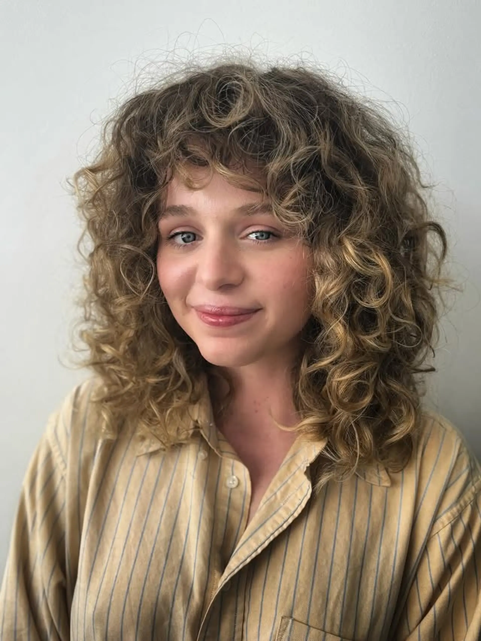 A medium-length curly shag with layered fringe bangs. 1