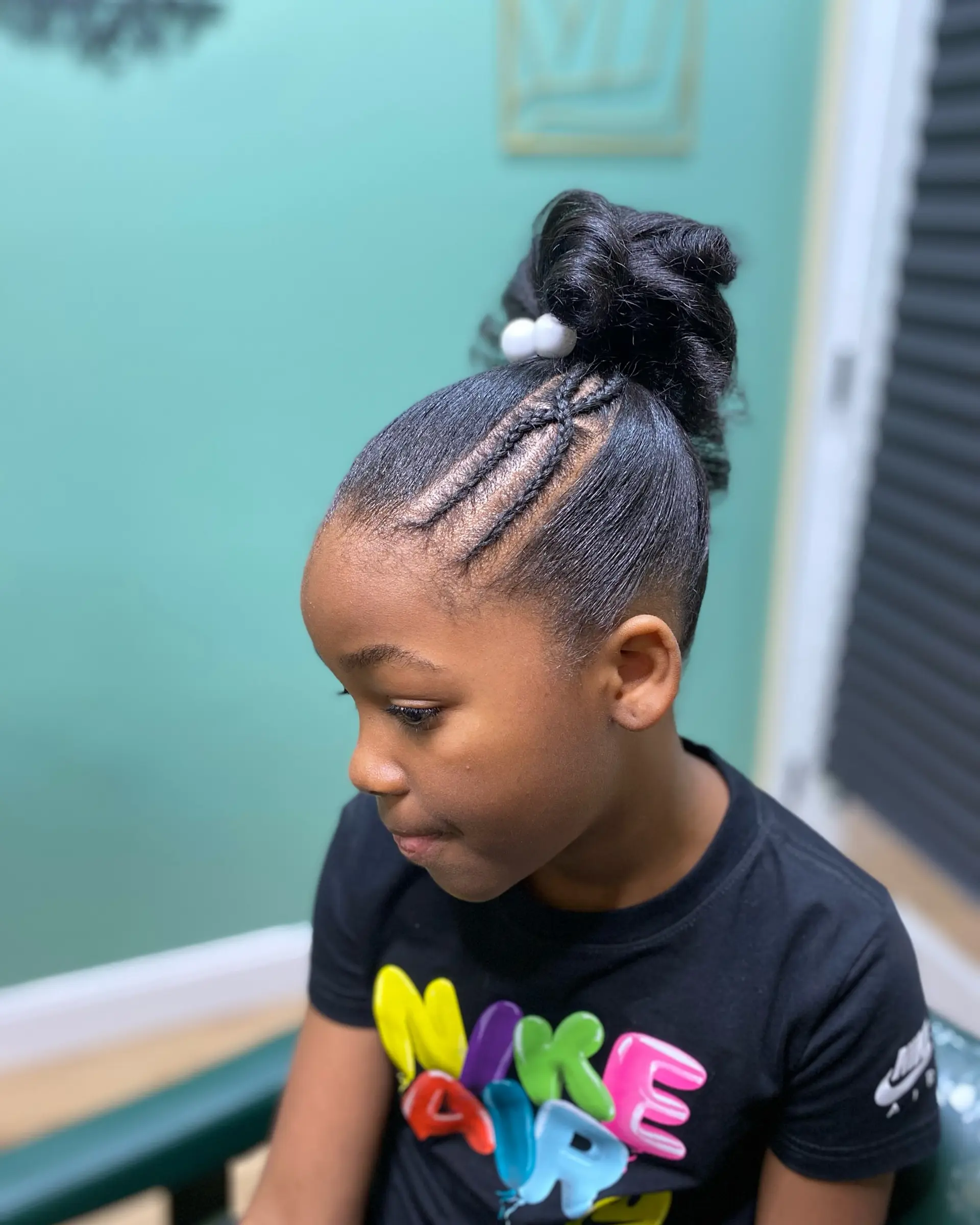 A sleek high bun featuring detailed side cornrow accents and secured with hair bobbles. 1