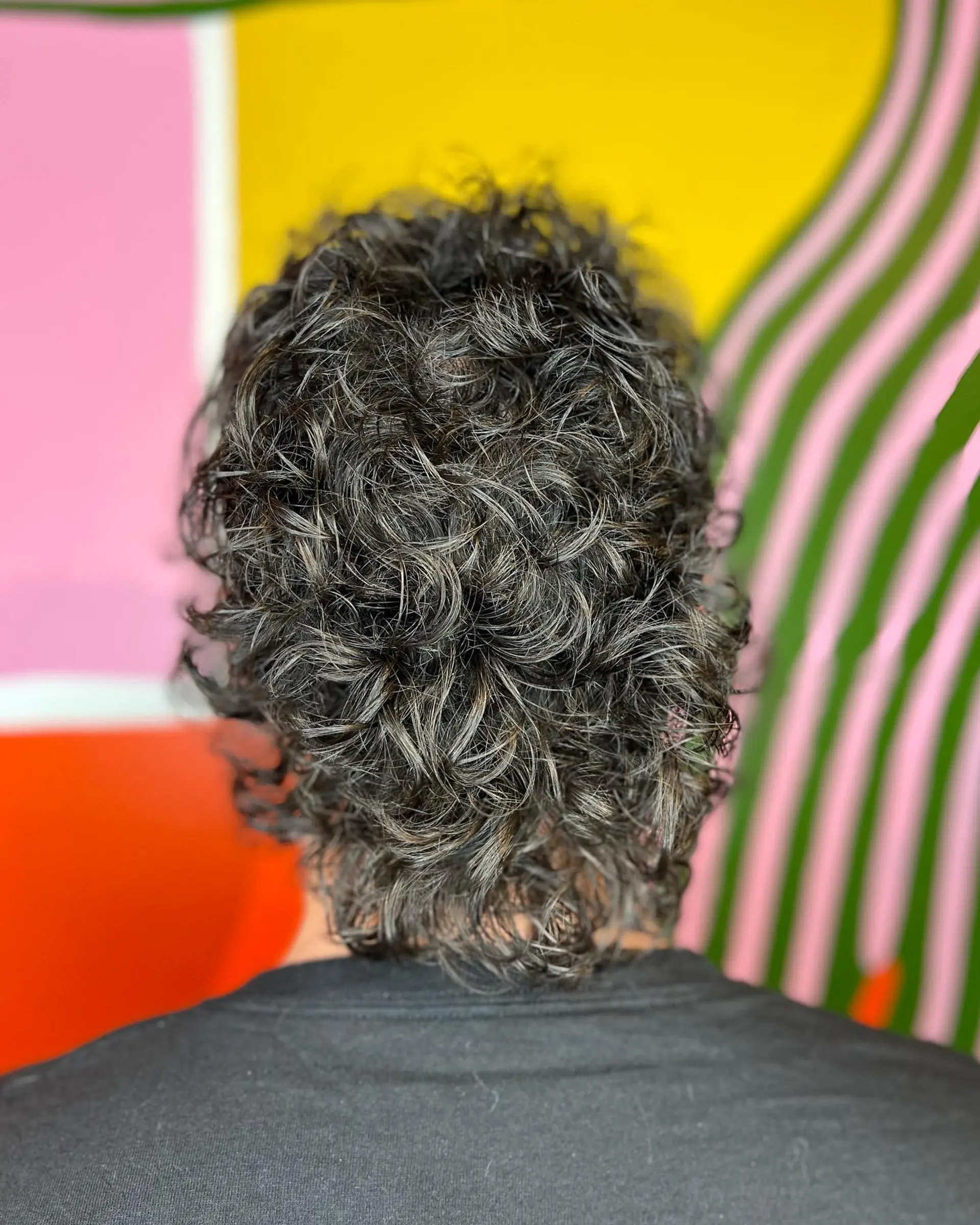 A textured curly mullet haircut with defined ringlets falling naturally to the nape. 1