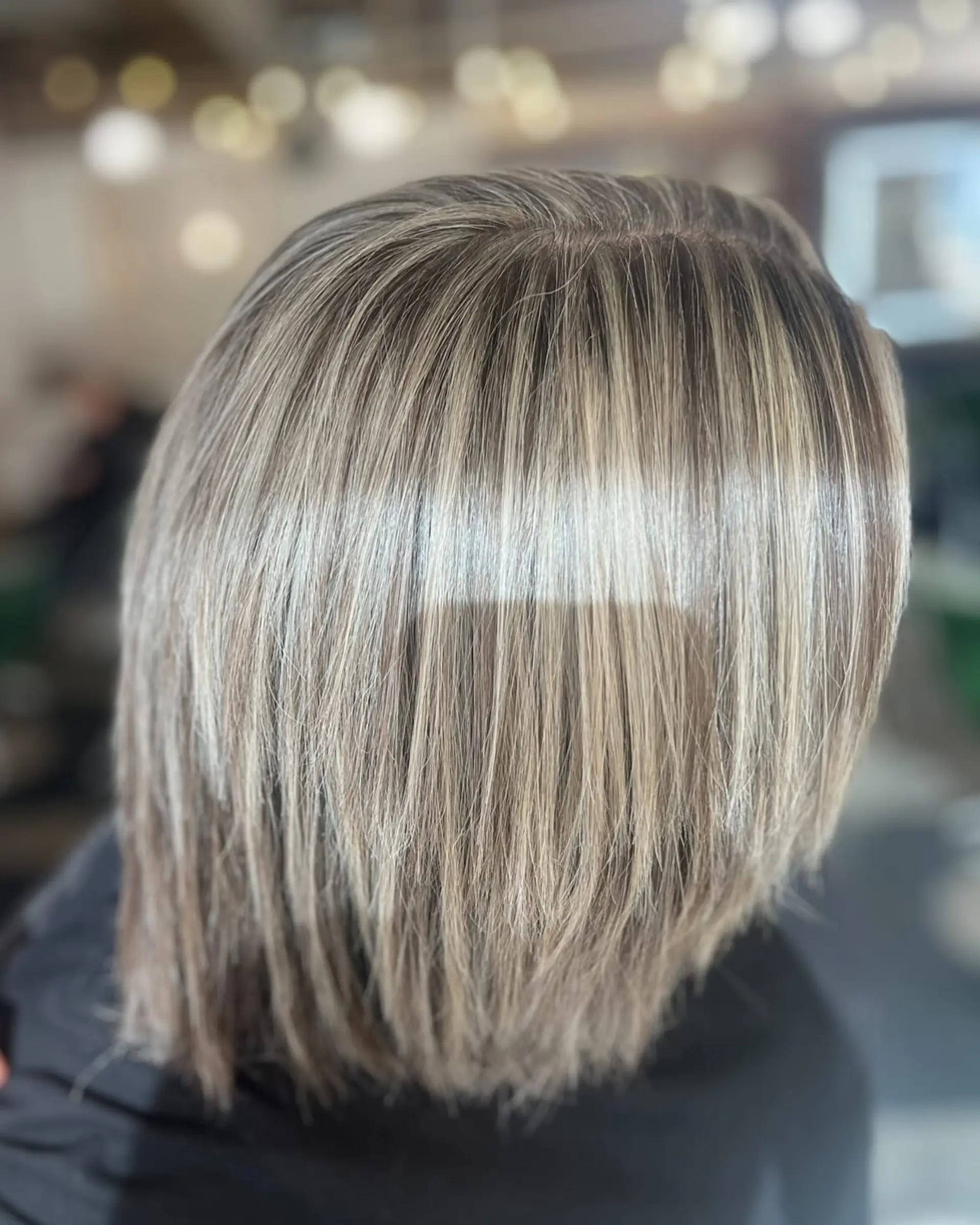A textured layered bob featuring fine, cool-toned ash blonde highlights seamlessly blended over a natural base. 1