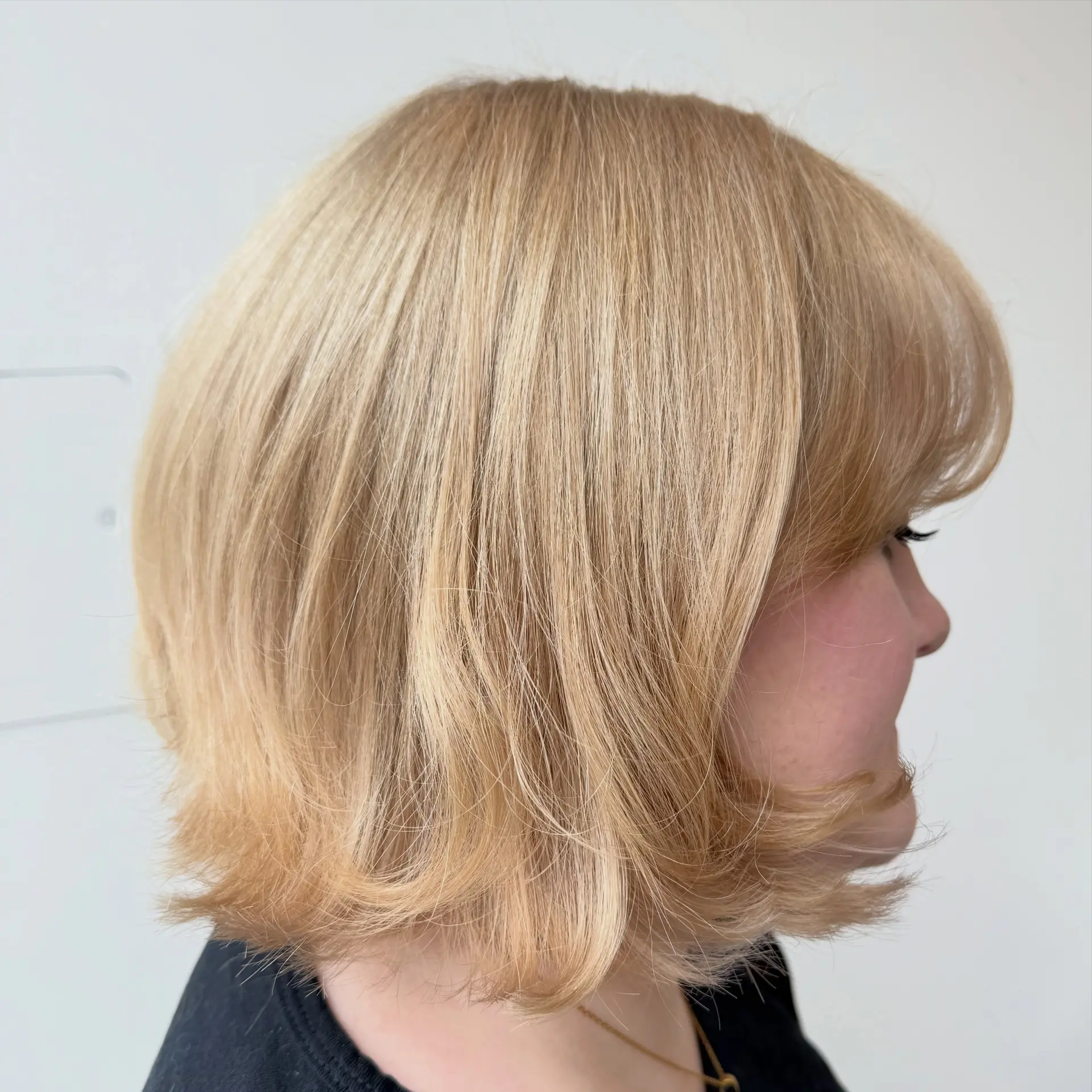 A short golden blonde bob haircut styled with subtle outward flipped ends and soft, face-framing fringe. 1