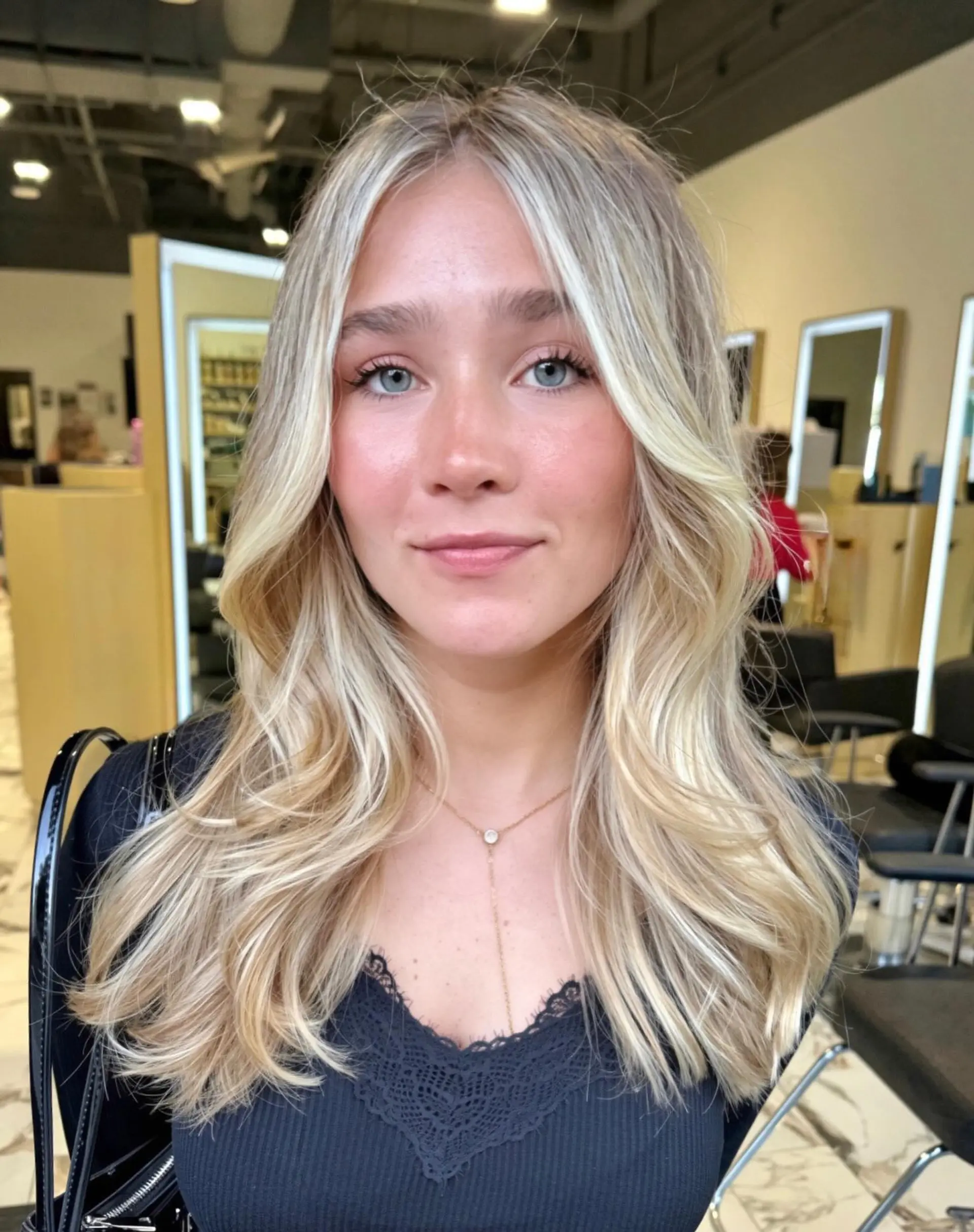 Bright dimensional blonde highlights styled with a center part and soft, face-framing waves. 1