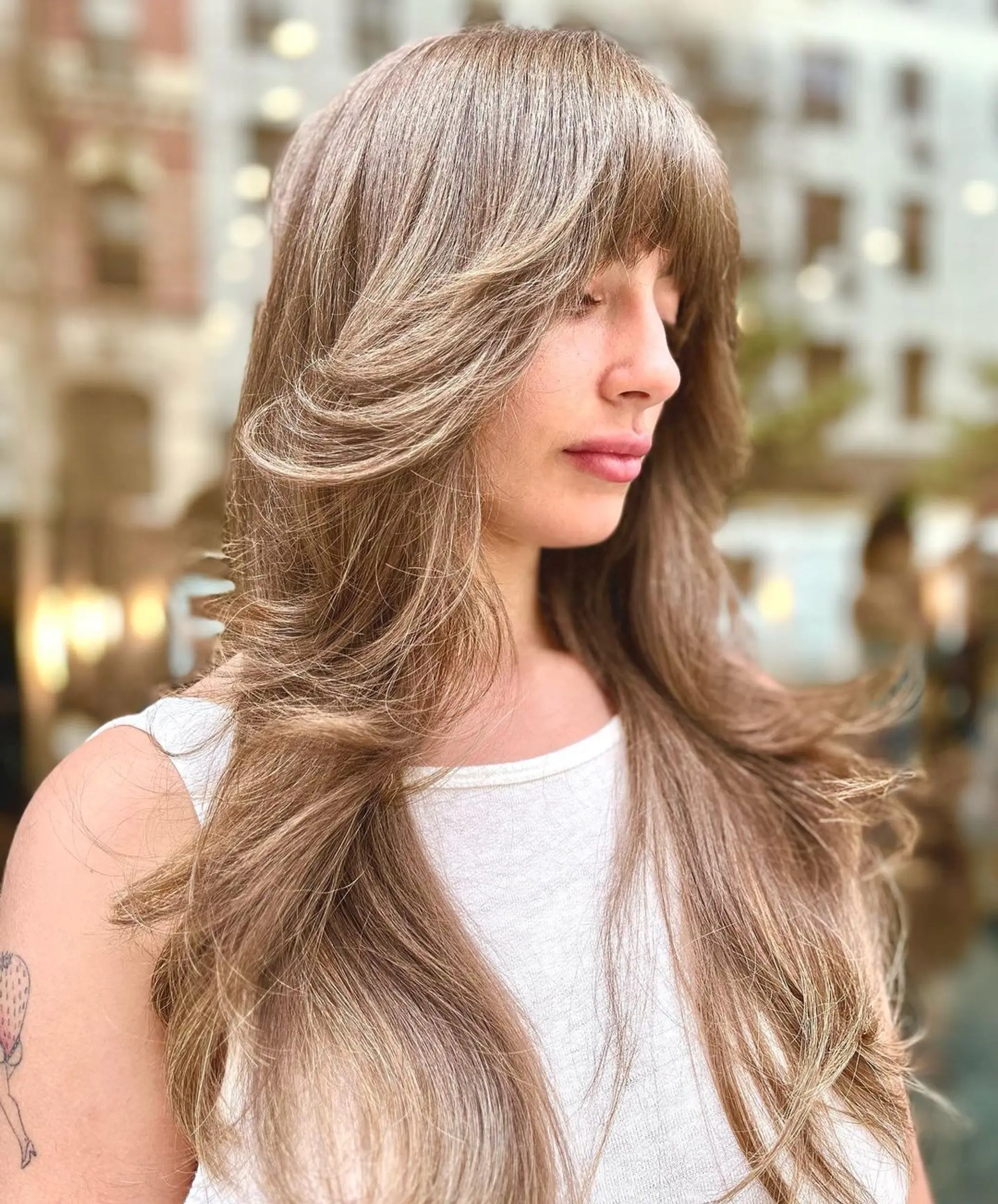 Very long, golden brown hair with honey blonde highlights. The hair is wavy, with a full fringe and face-framing layers. 1