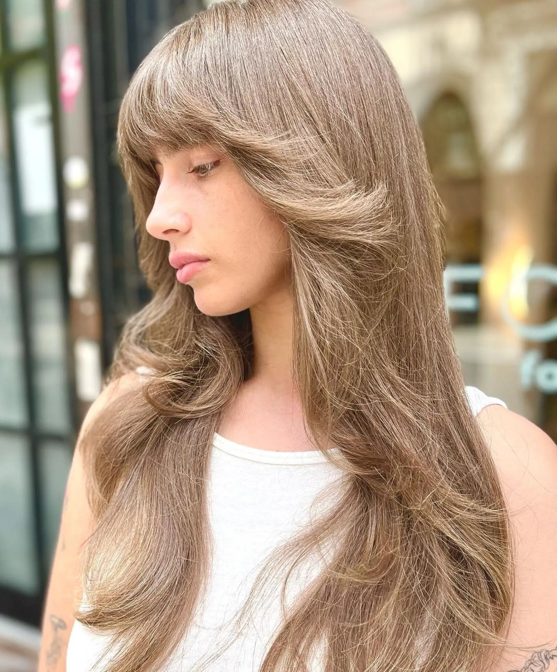 Very long, golden brown hair with honey blonde highlights. The hair is wavy, with a full fringe and face-framing layers. 2