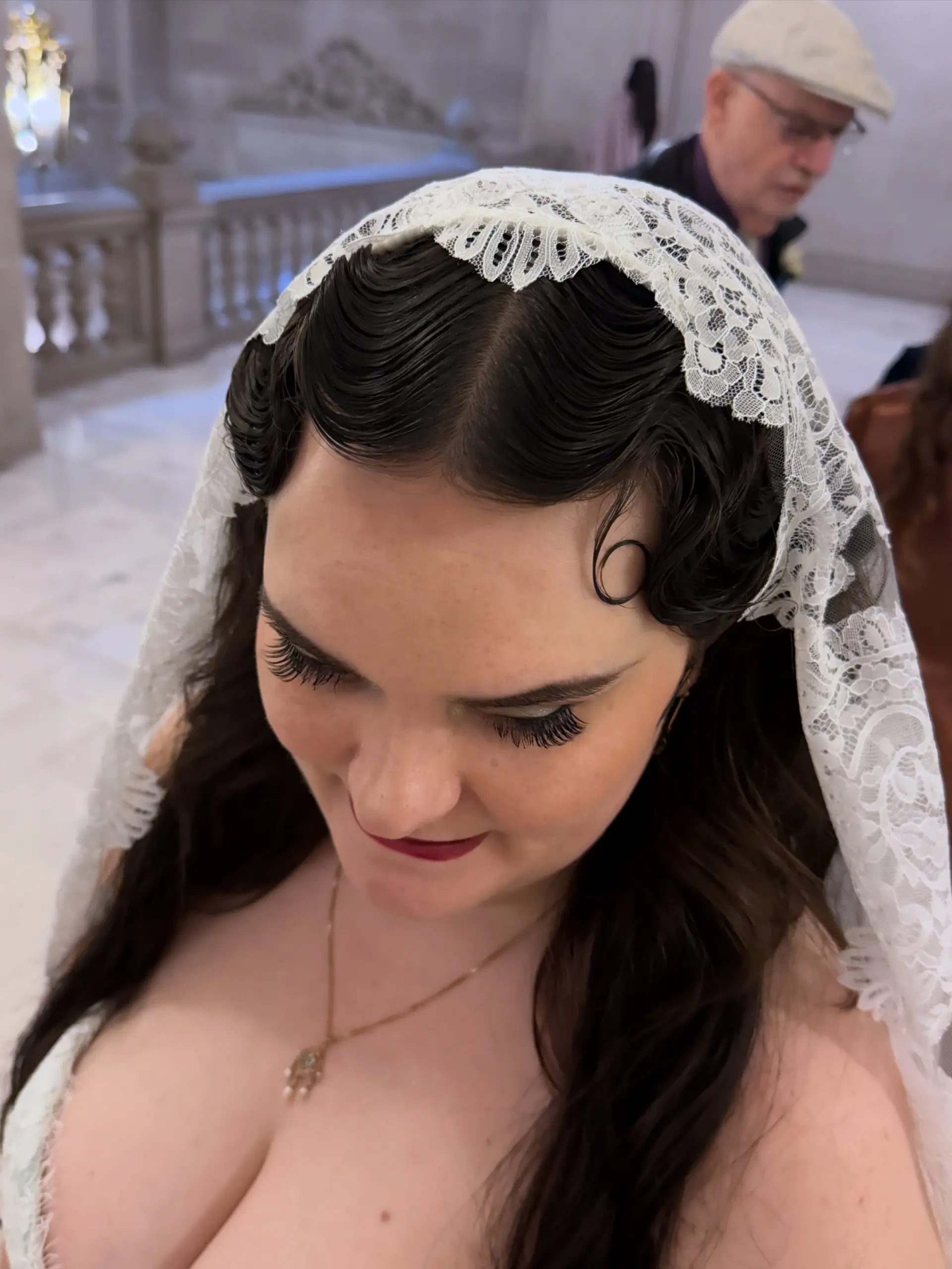 Classic vintage finger waves sculpted closely to the hairline, styled with flowing dark hair and an ornate lace veil. 1
