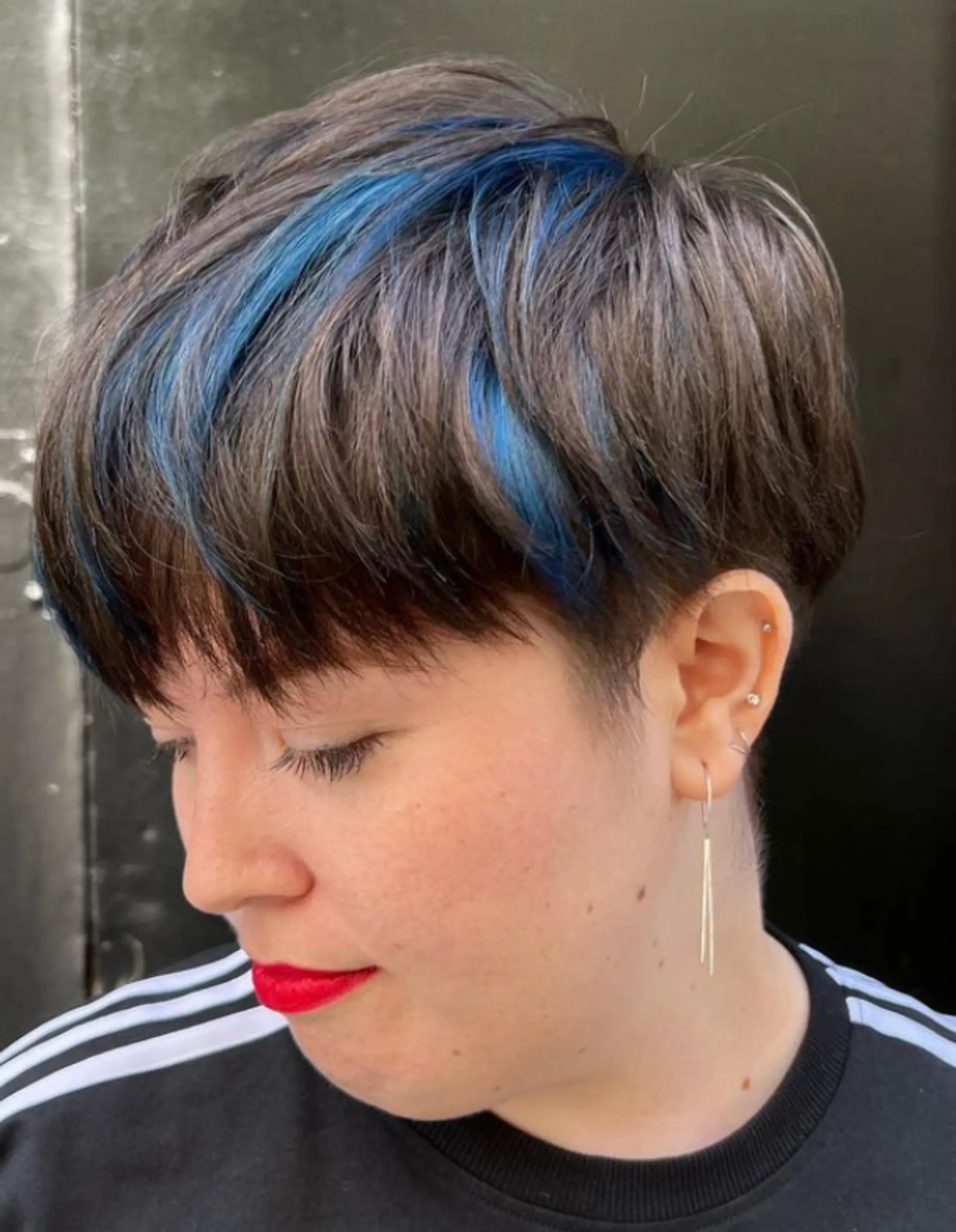 This chic and modern hairstyle features a short, straight pixie cut with vivid blue streaks. The hair is layered and includes an undercut, with a fringe sweeping gently across the forehead, adding bold and playful elements to the look.

Color by @simabeautynyc
Cut and style by @juliamannino_hair
 1