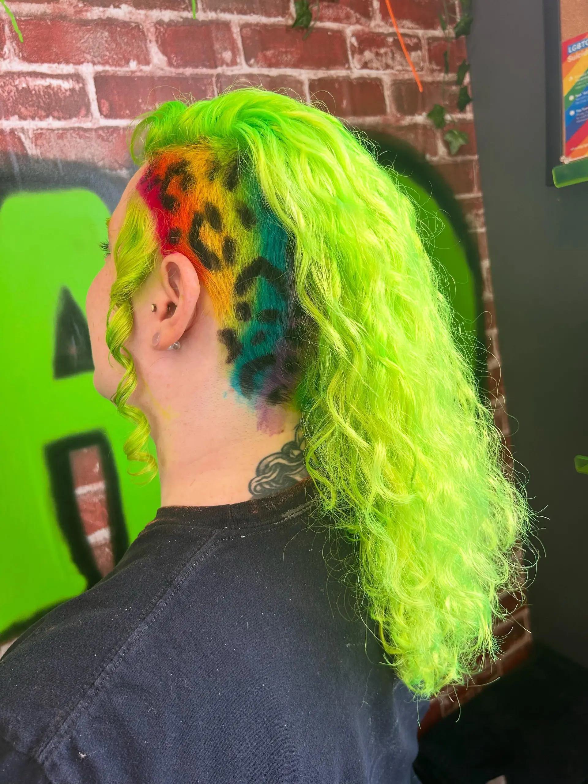 Vibrant neon lime green curls styled to the side, revealing a shaved undercut adorned with a rainbow gradient and black leopard spots. 1