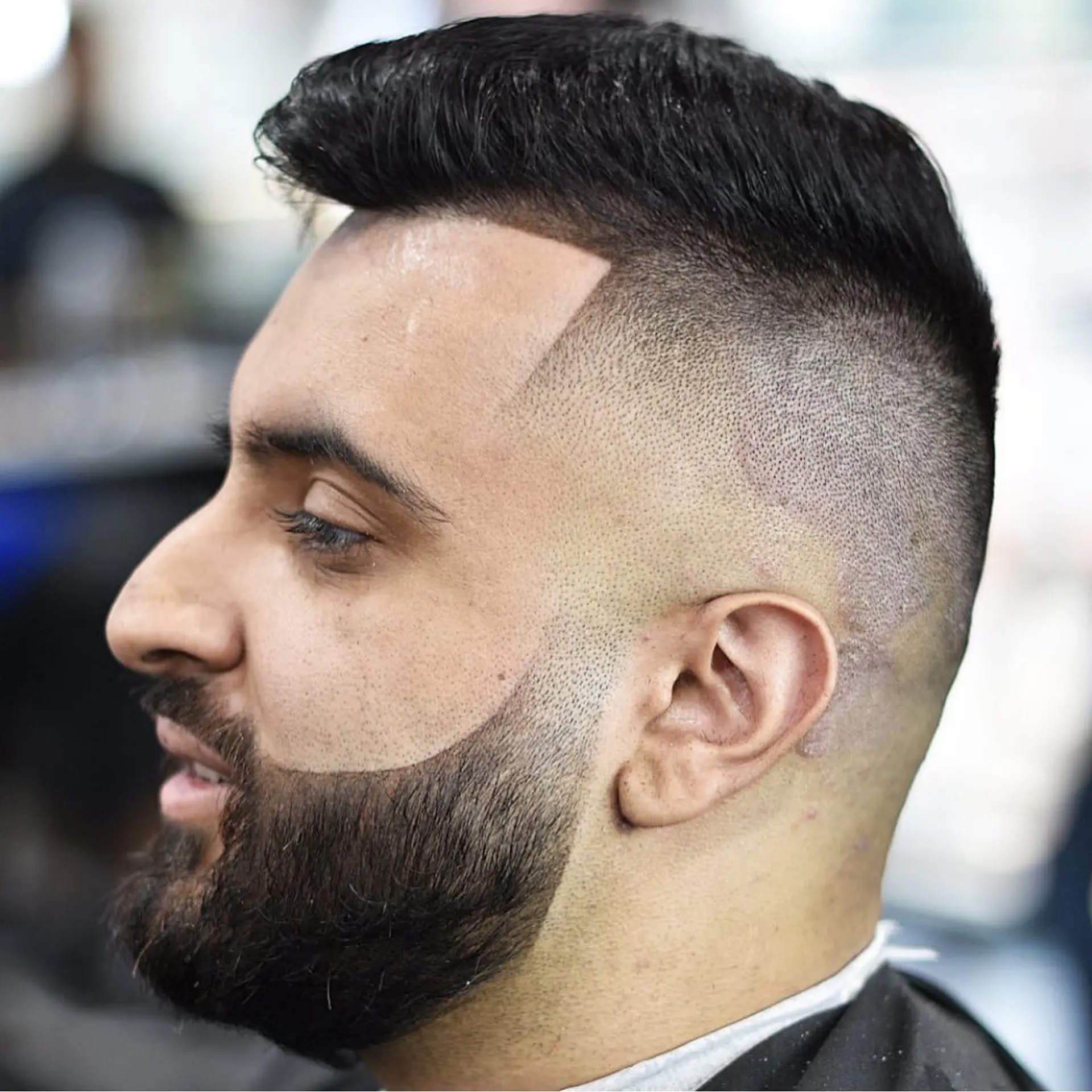 A high skin fade with a crisp edge-up, short styled top, and a precisely defined beard contour. 1