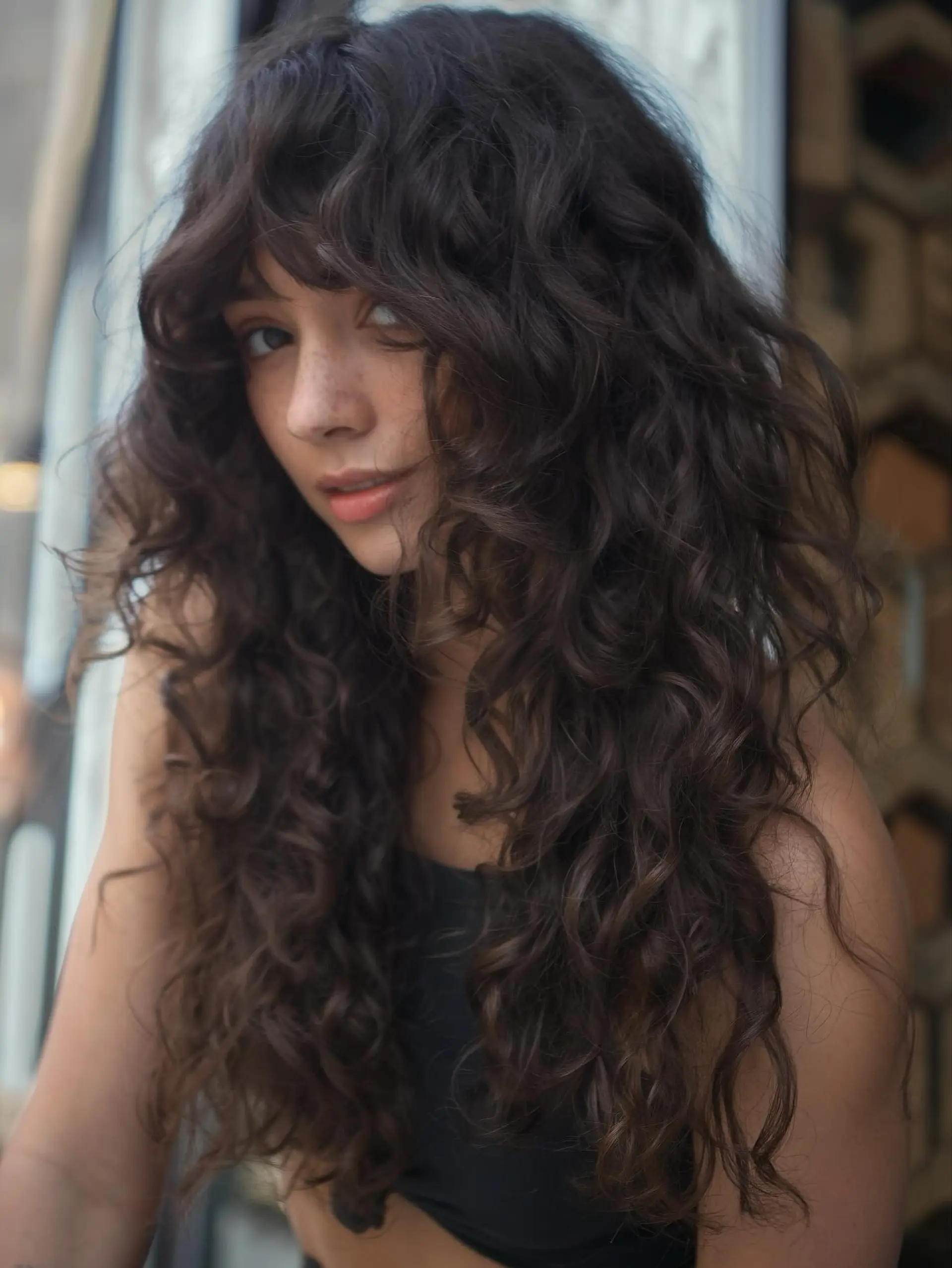 Voluminous long dark brown curls layered in a shag silhouette with face-framing curly bangs. 1