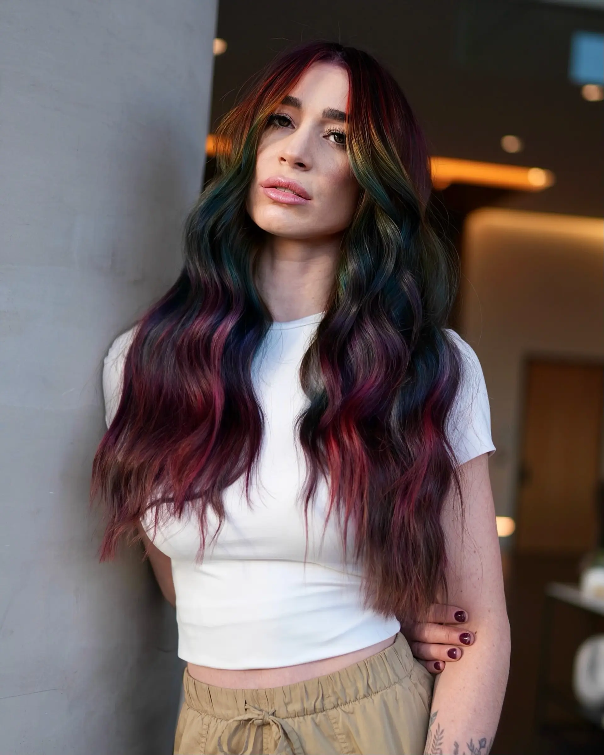 Long dark hair accented with vivid prism ribbons of ruby red, purple, blue, and green, styled in soft waves. 1