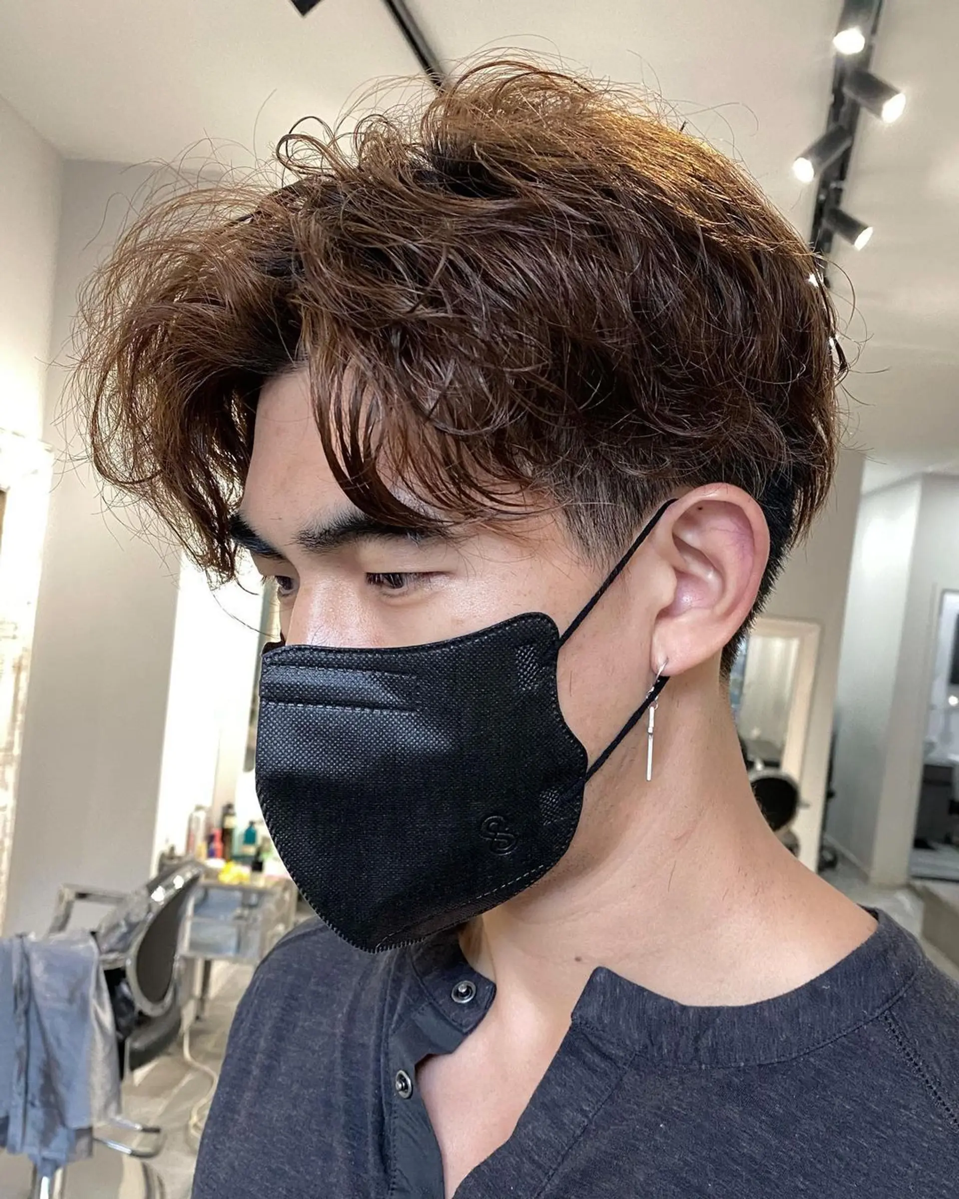 Medium-length wavy honey brown hair with voluminous, tousled waves on top, giving a natural lift and messy, layered appearance. The sides and back are slightly shorter to accentuate the textured flow on top. 1