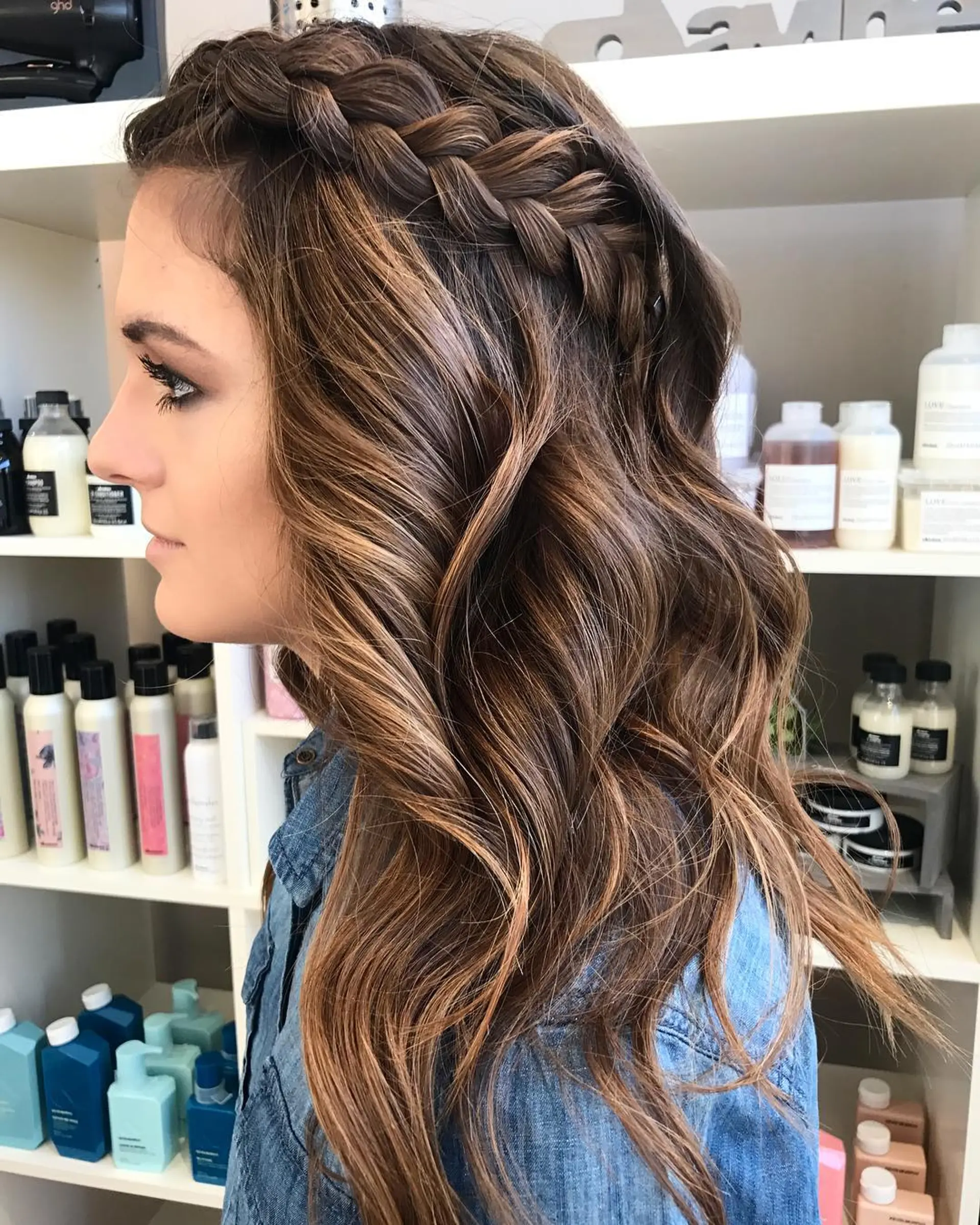 Long dimensional brunette hair styled in loose beach waves with a prominent side Dutch braid crown. 1