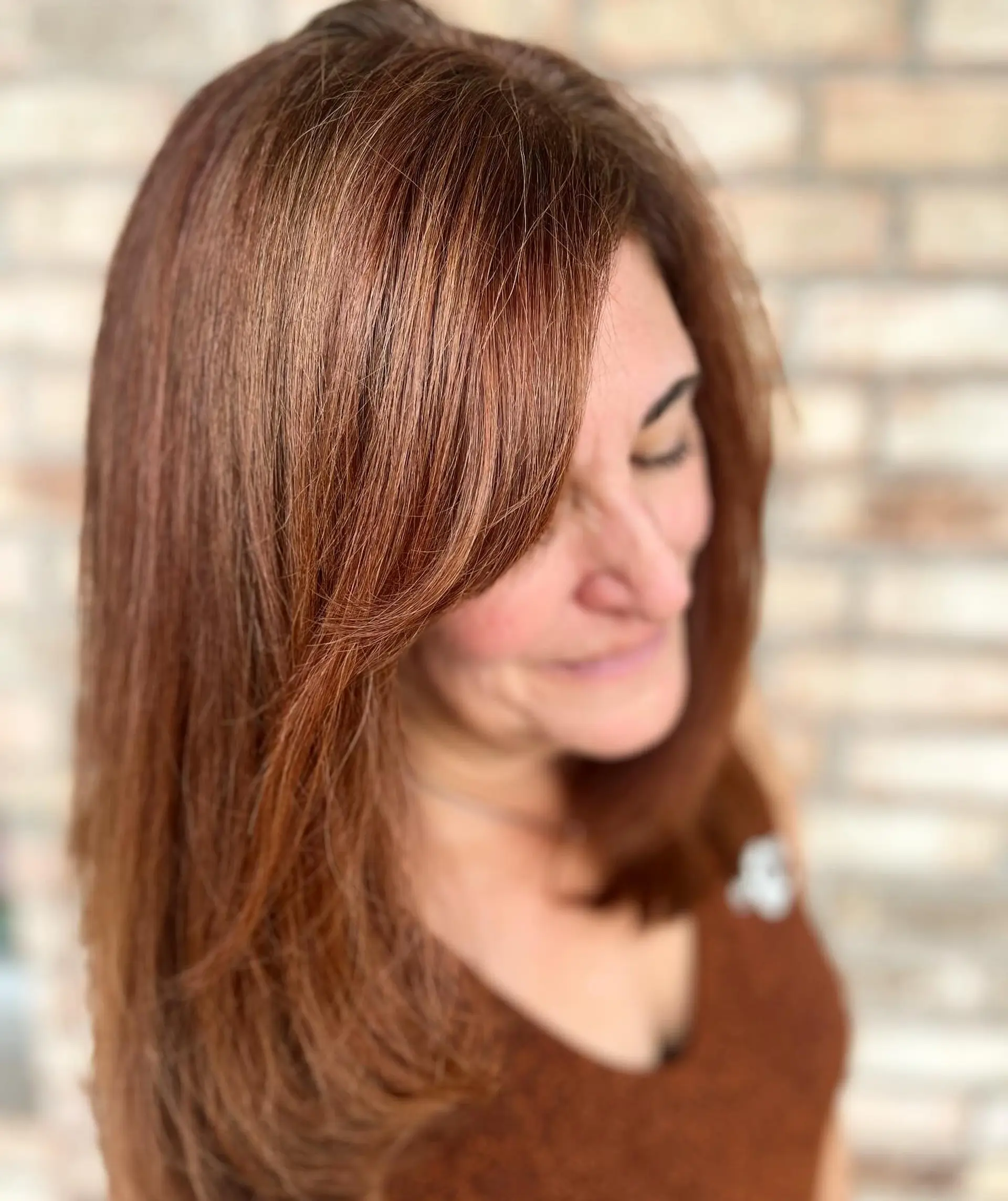 Medium-length warm auburn hair styled in a smooth blowout with side-swept face-framing layers. 1