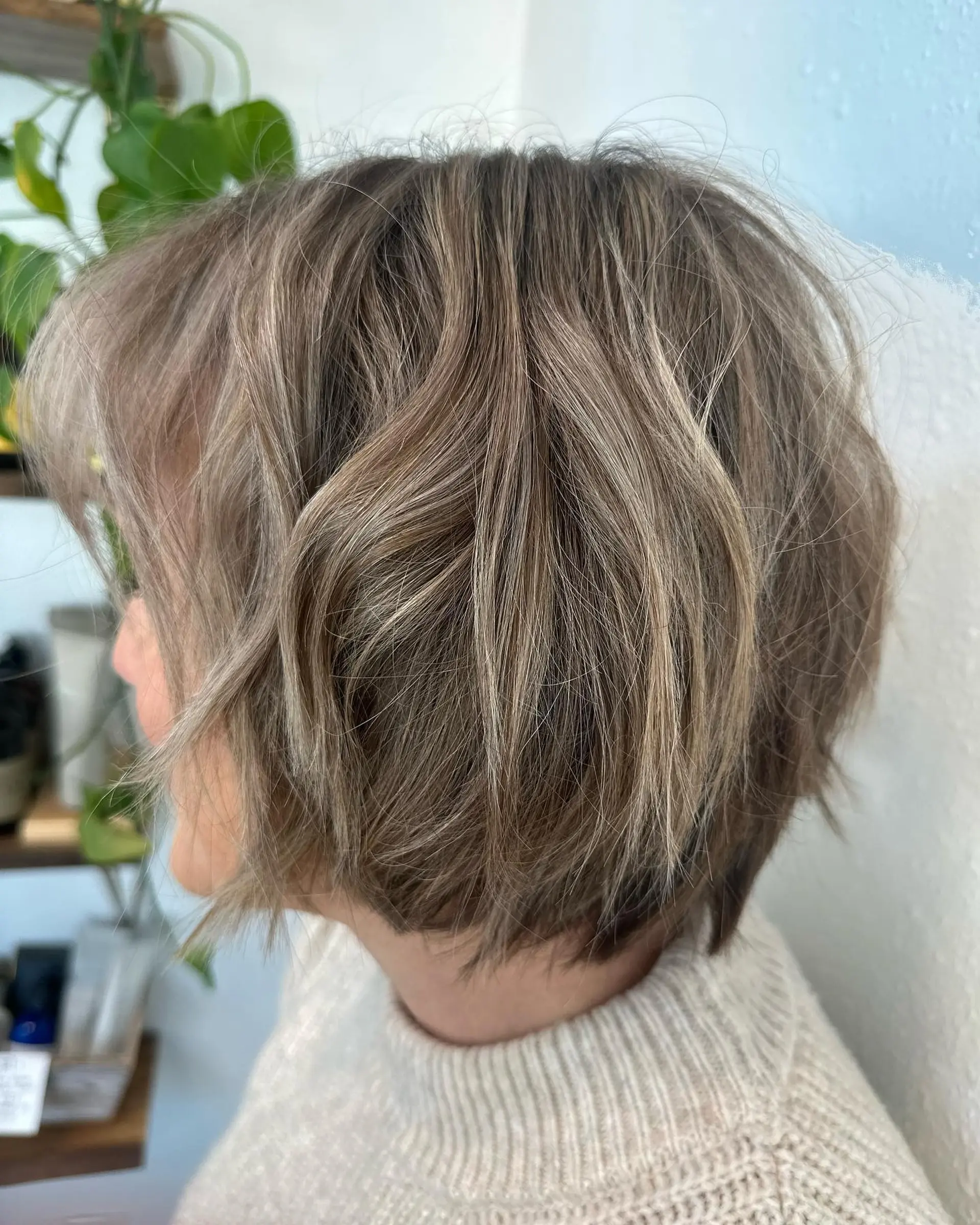 A textured, chin-length graduated bob with soft layering and finely woven cool-toned highlights. 1
