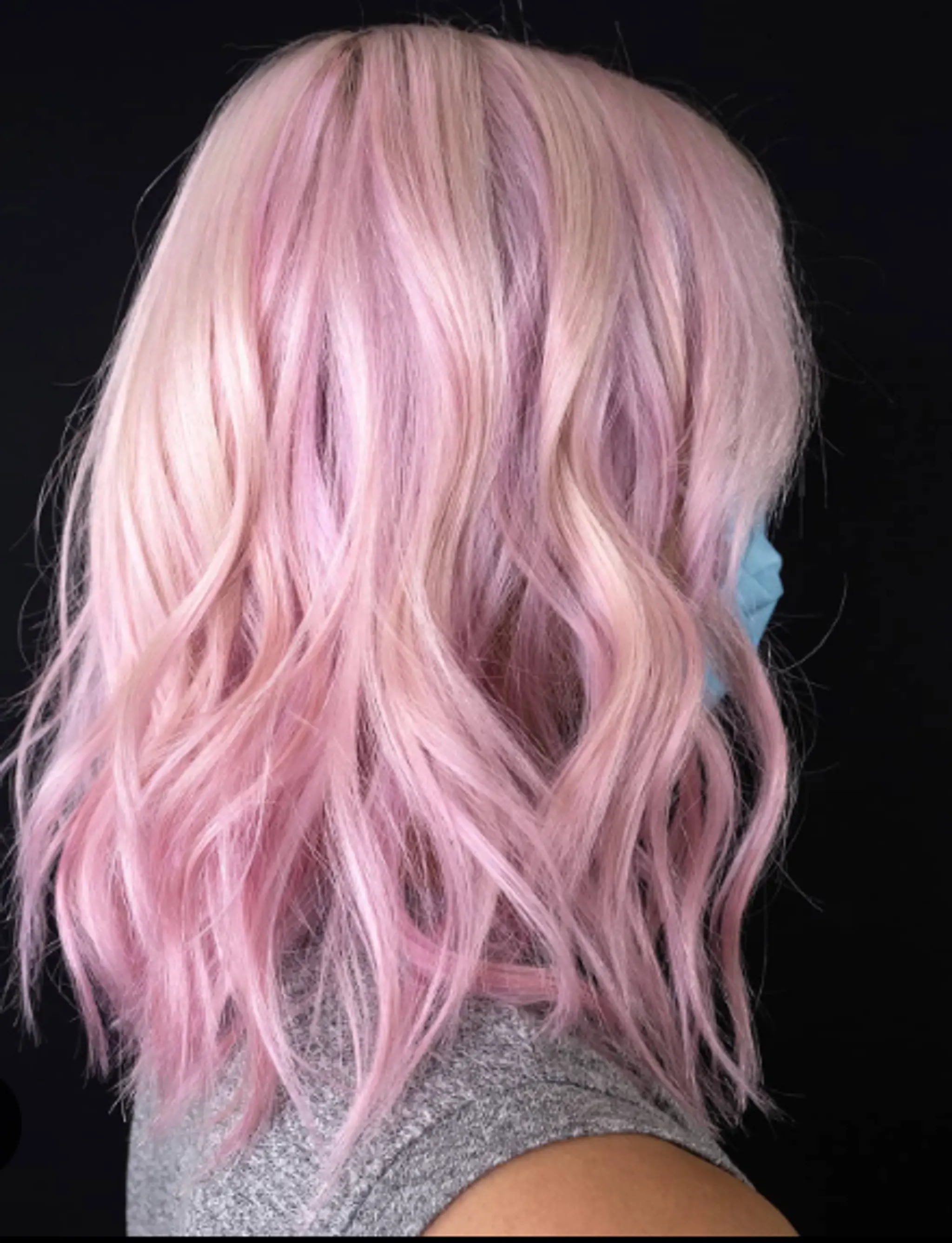 Medium-length wavy hair with loose waves and dyed a vivid pastel pink. Soft texture and voluminous flow.