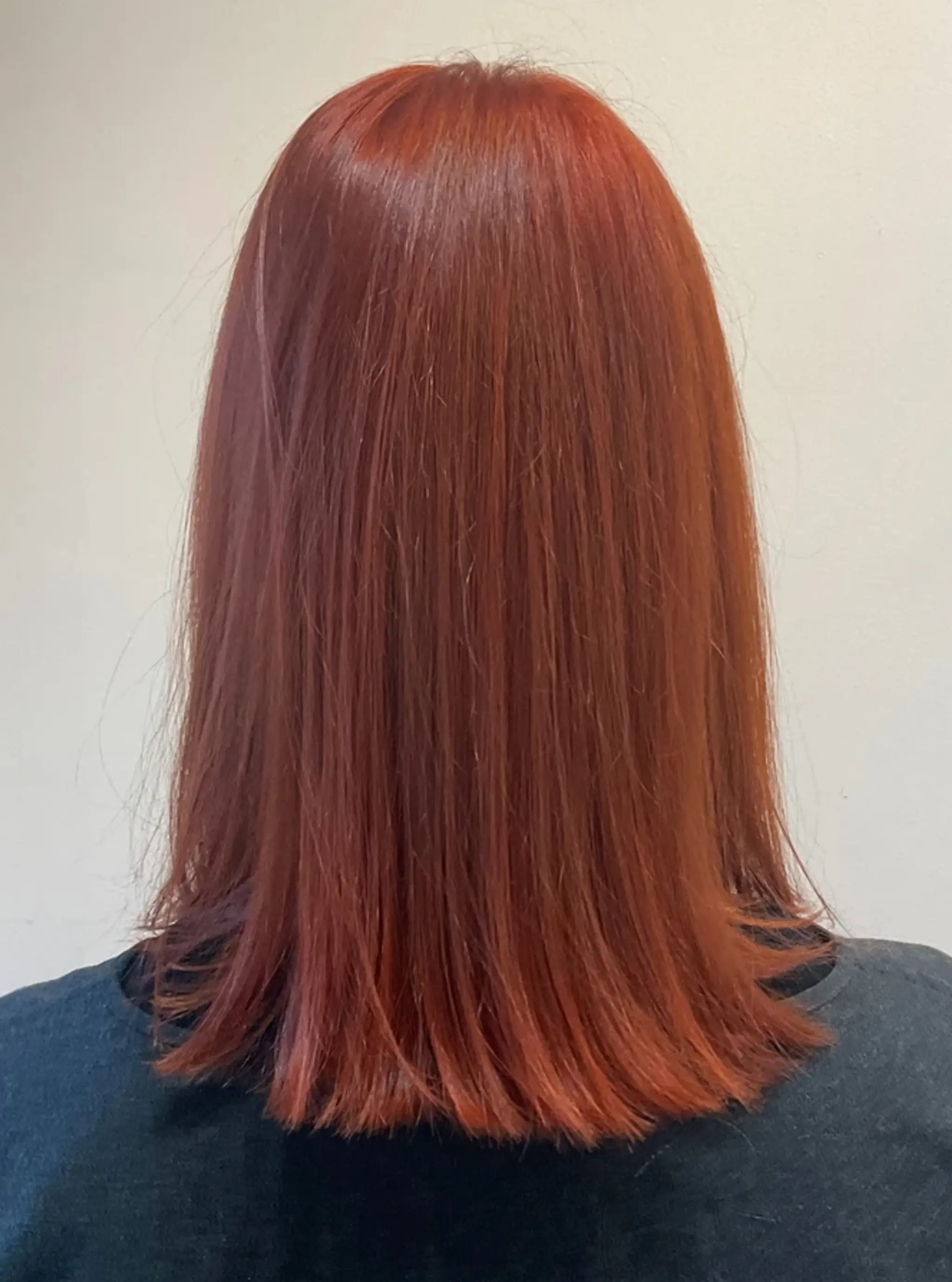 A sleek, straight copper hairstyle with a glossy shine and medium length.