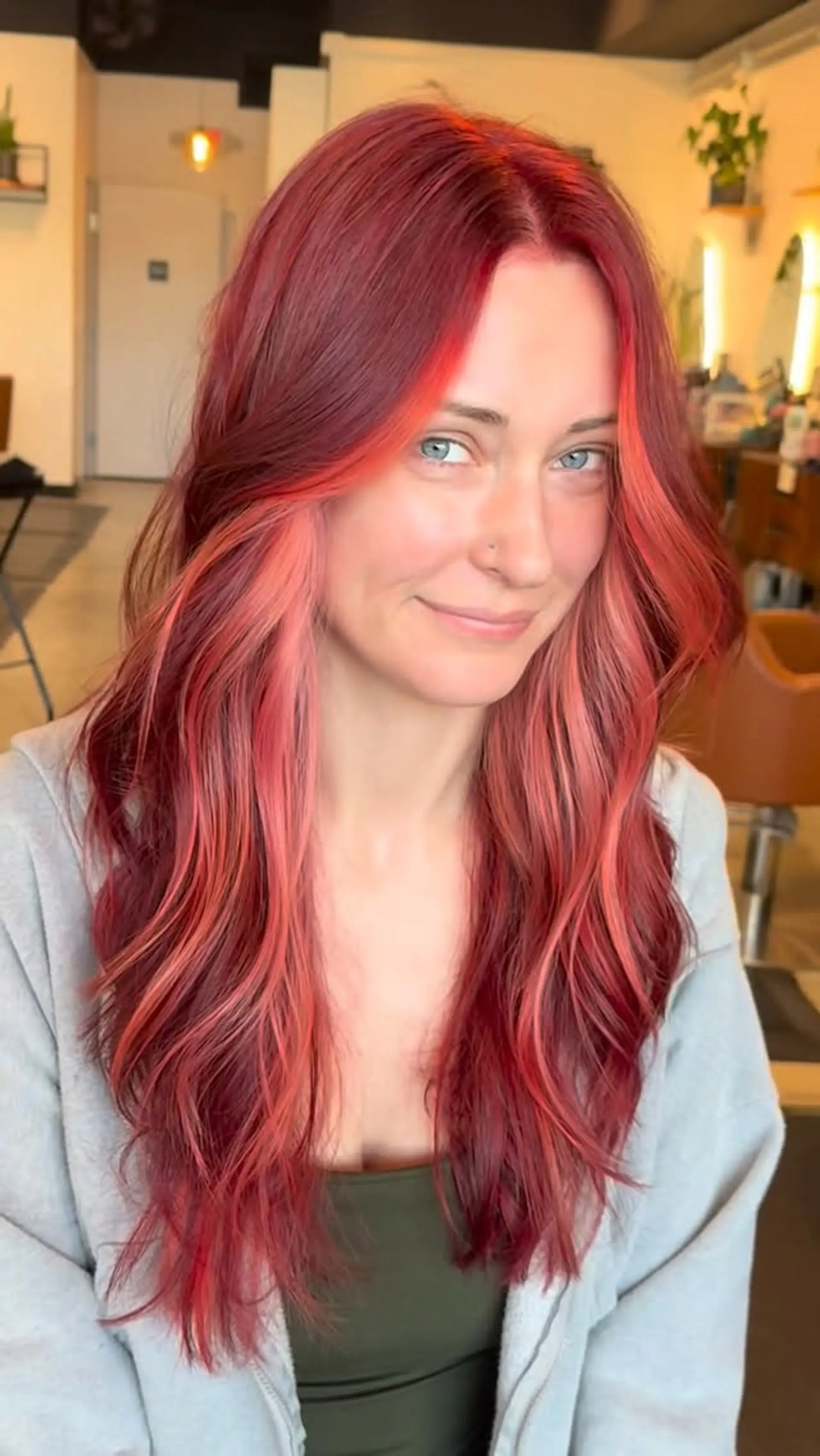 Long wavy strawberry-red hair styled with a vibrant coral-peach face-framing money piece. 1