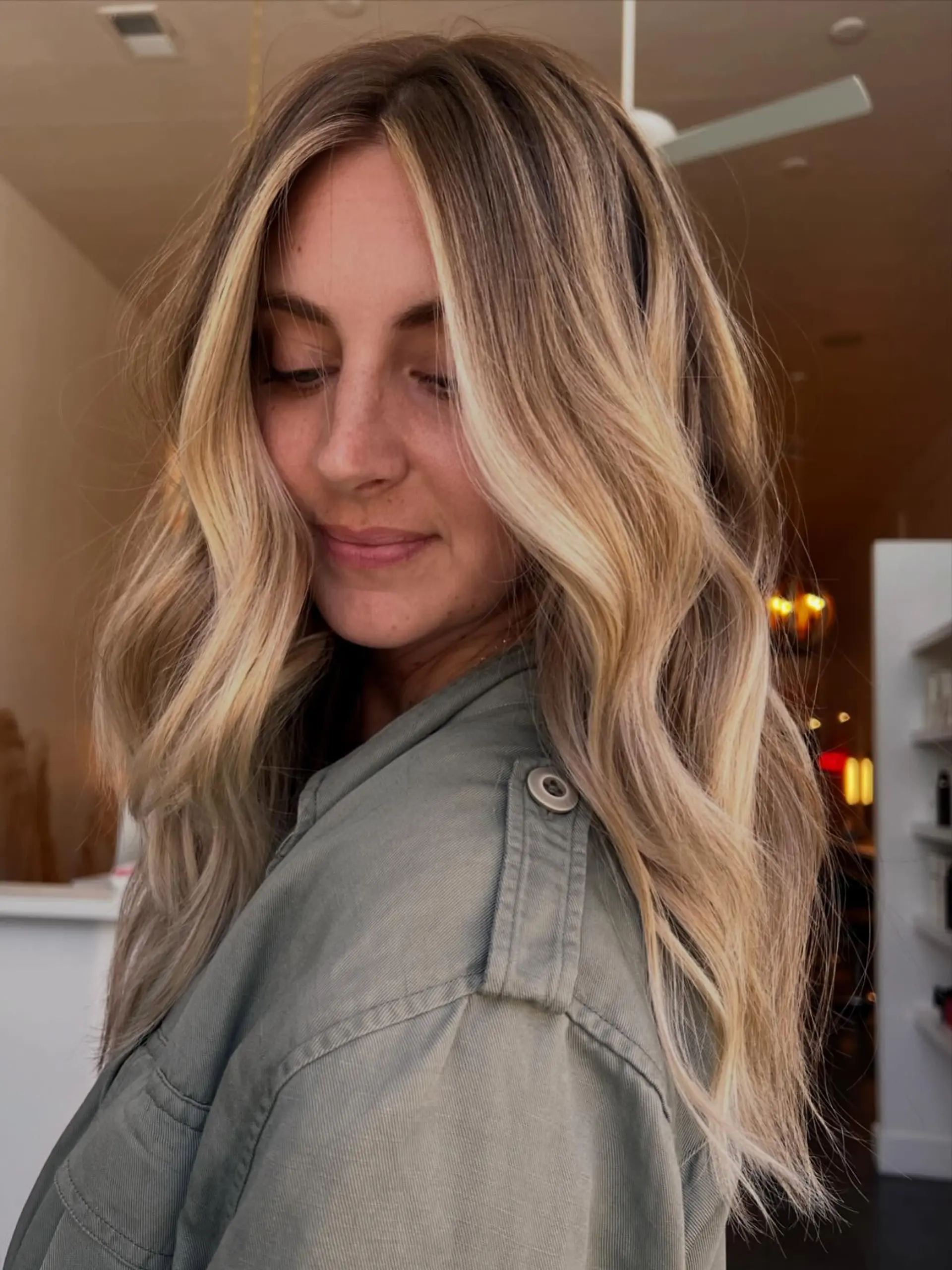 Long lived-in blonde hair with face-framing highlights, styled into soft dimensional waves. 1