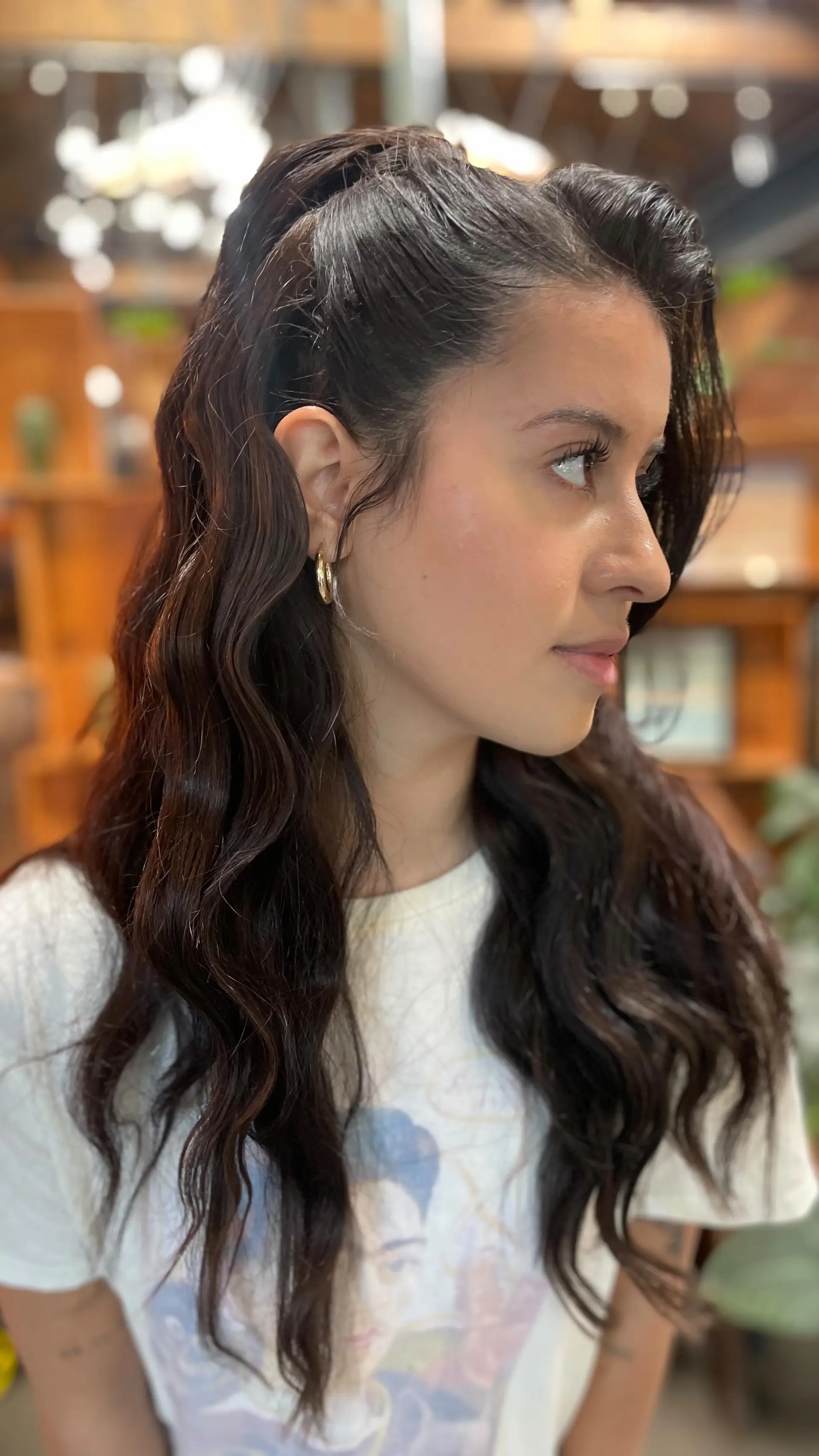 Long dark brown hair styled with glossy, defined waves and swept up into a high half-ponytail. 1