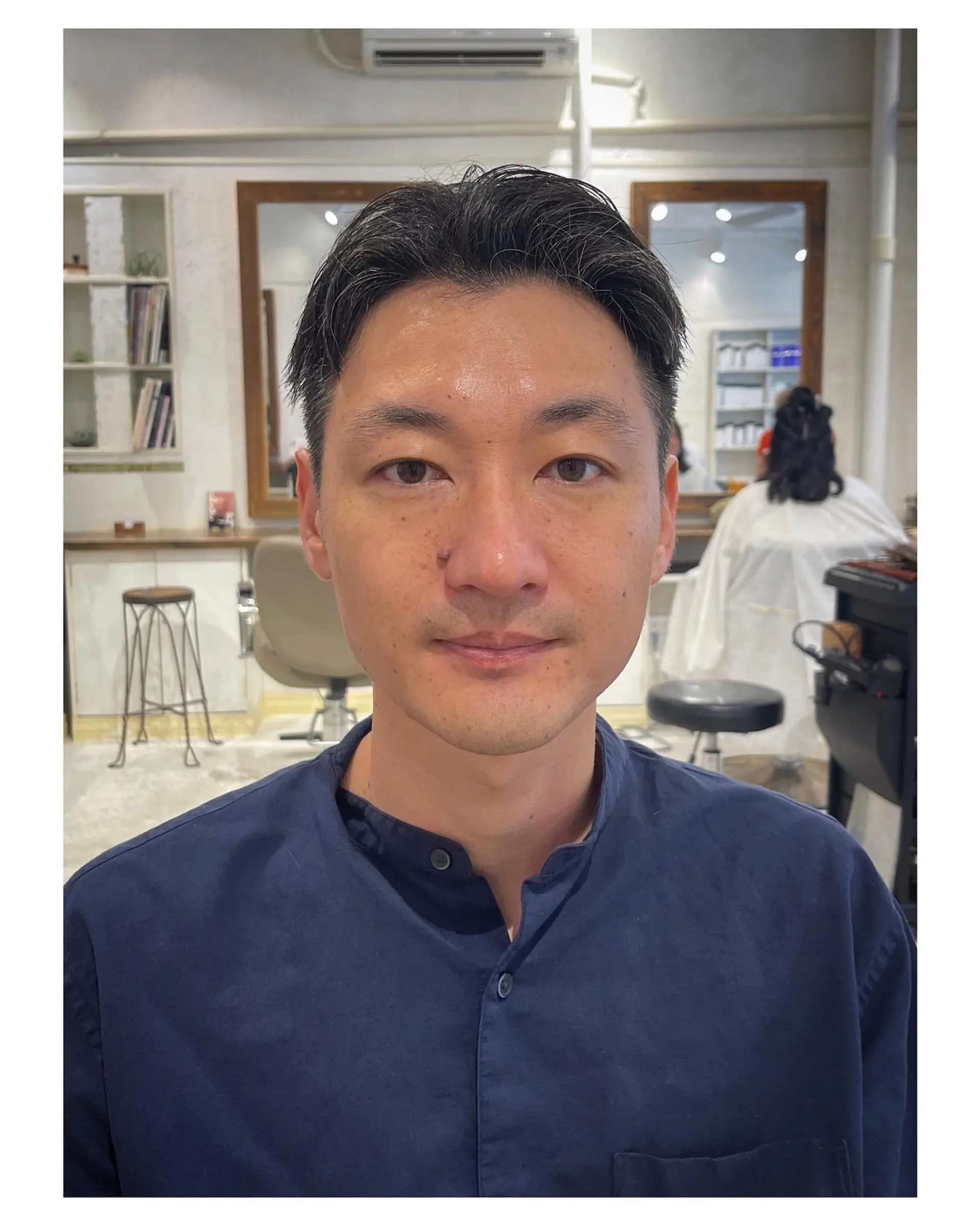 A clean, tapered short men's haircut styled with a center parting and hair pushed neatly back off the face. 1