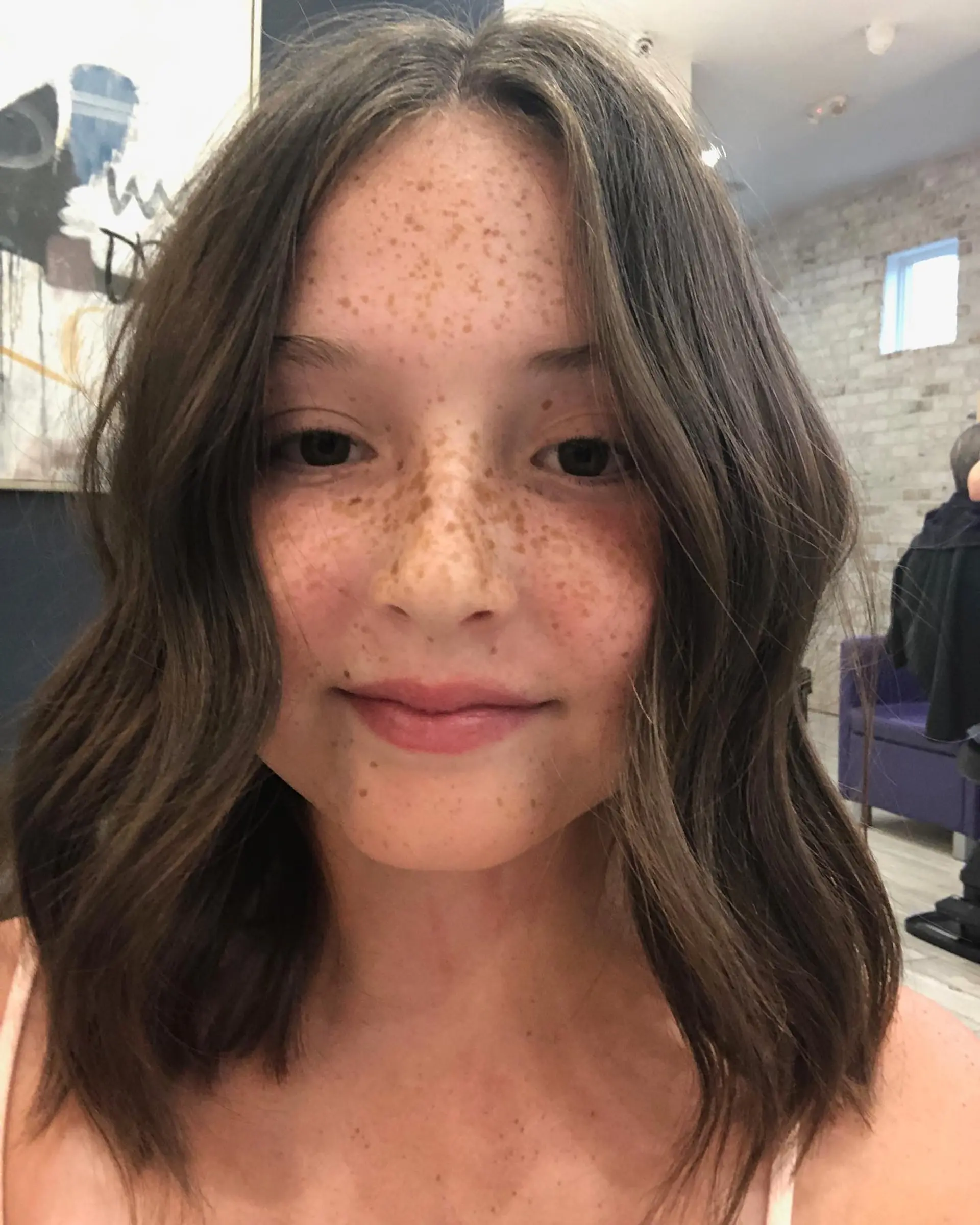 A shoulder-length brunette lob styled with loose, effortless waves and a center part. 1