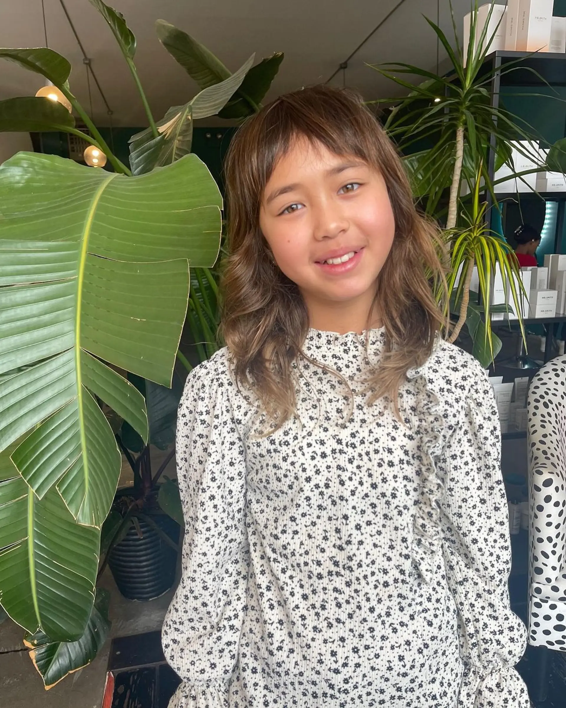 Medium-length wavy hair with soft fringe and subtle layers, accentuated by golden highlights. 1