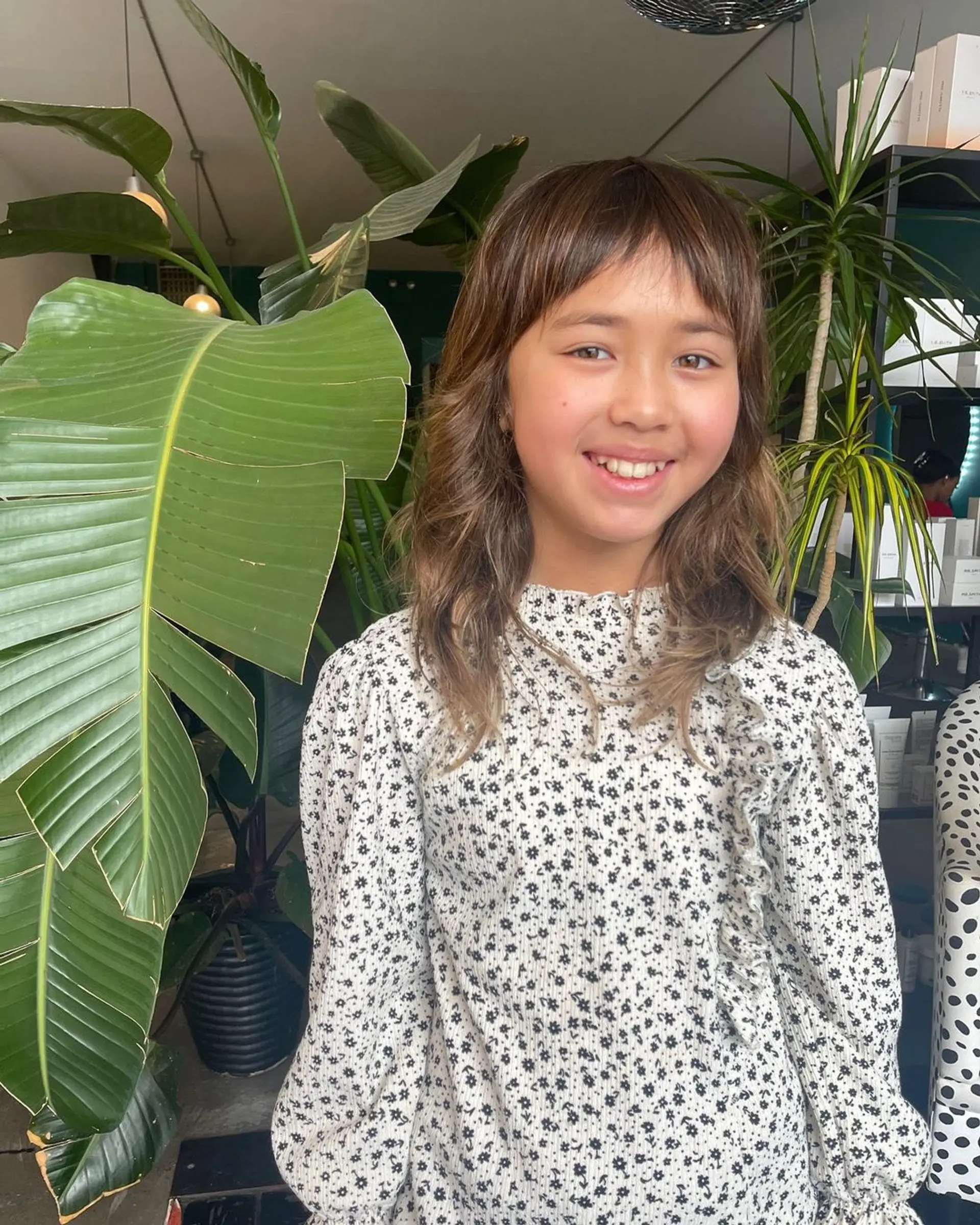 Medium-length wavy hair with soft fringe and subtle layers, accentuated by golden highlights. 2