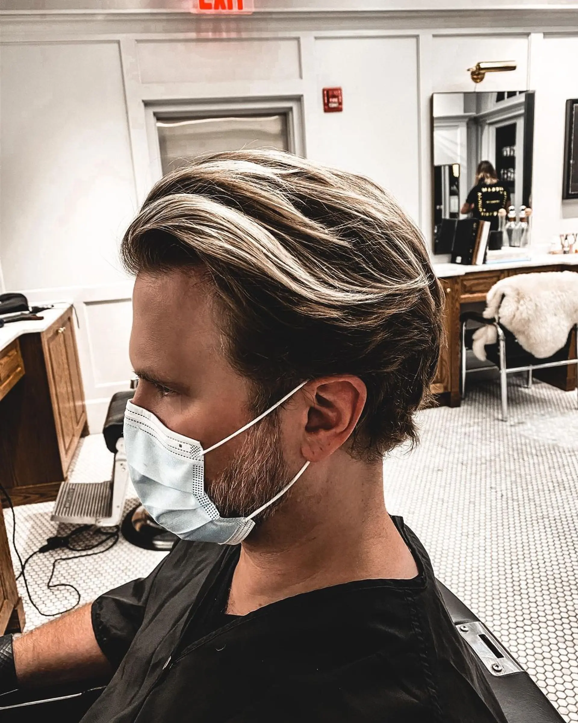 A sophisticated hairstyle with medium-length, straight light brown hair and subtle blond highlights. The style features volume at the crown, smoothly brushed back hair, and neatly faded sides, complemented by a well-groomed beard. 2