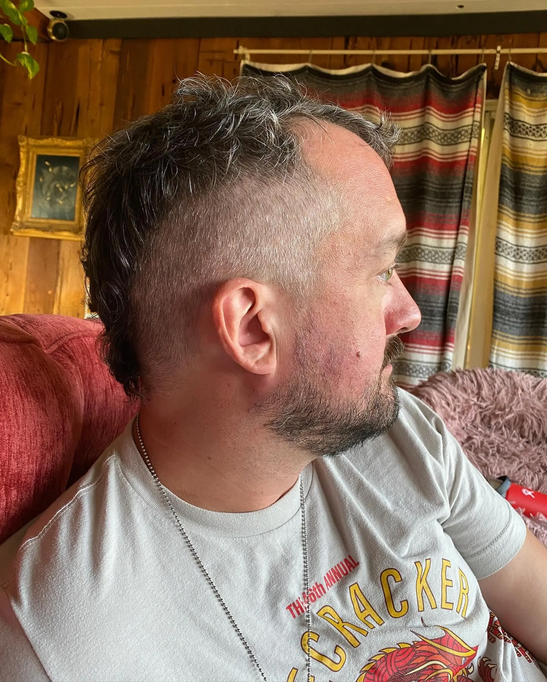 A playful short haircut featuring shaved sides with a textured strip along the top and back in a mini-mohawk style. 1