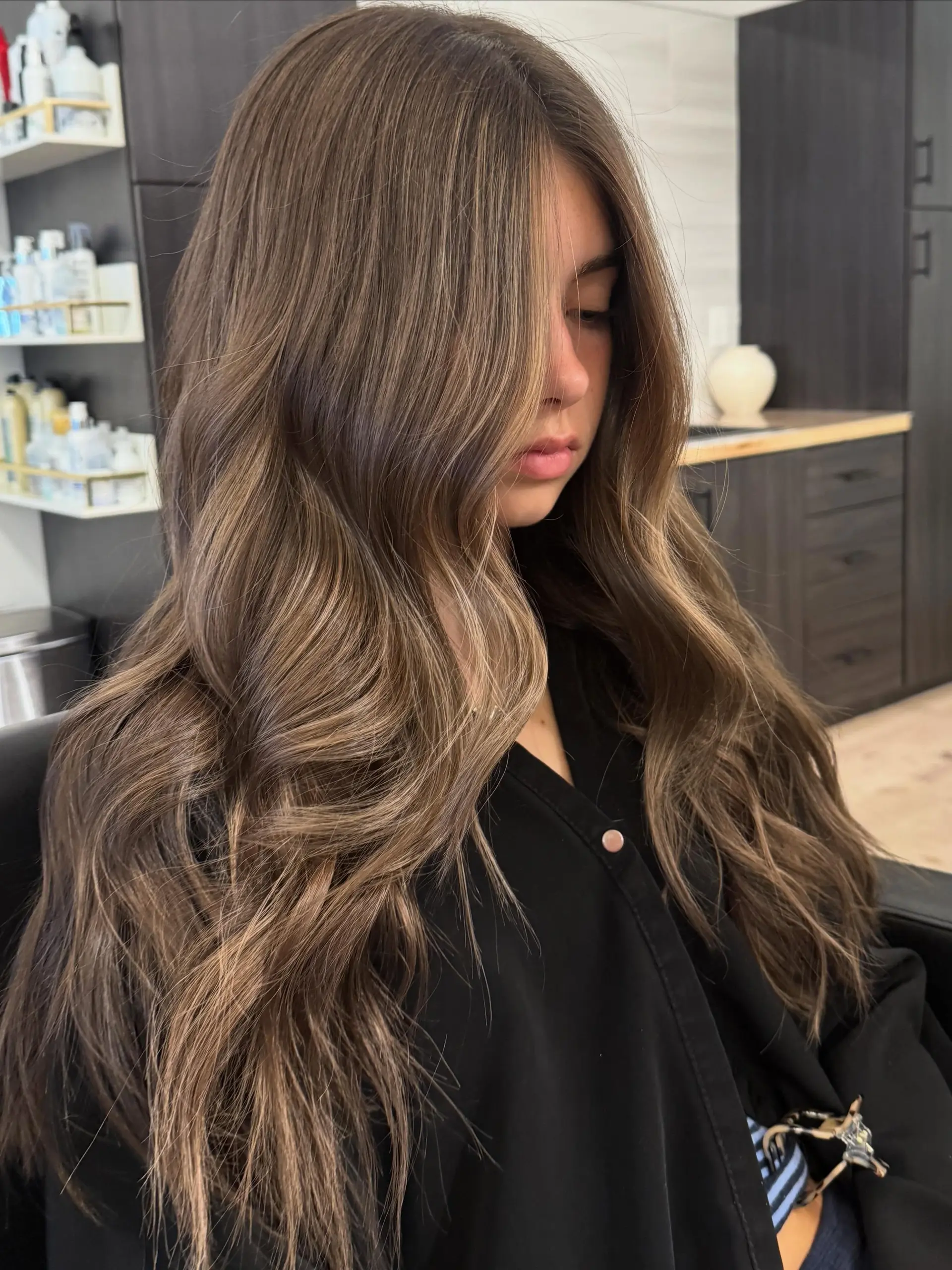 Long dimensional brunette hair styled in loose, flowing waves with subtle lighter brown highlights. 1