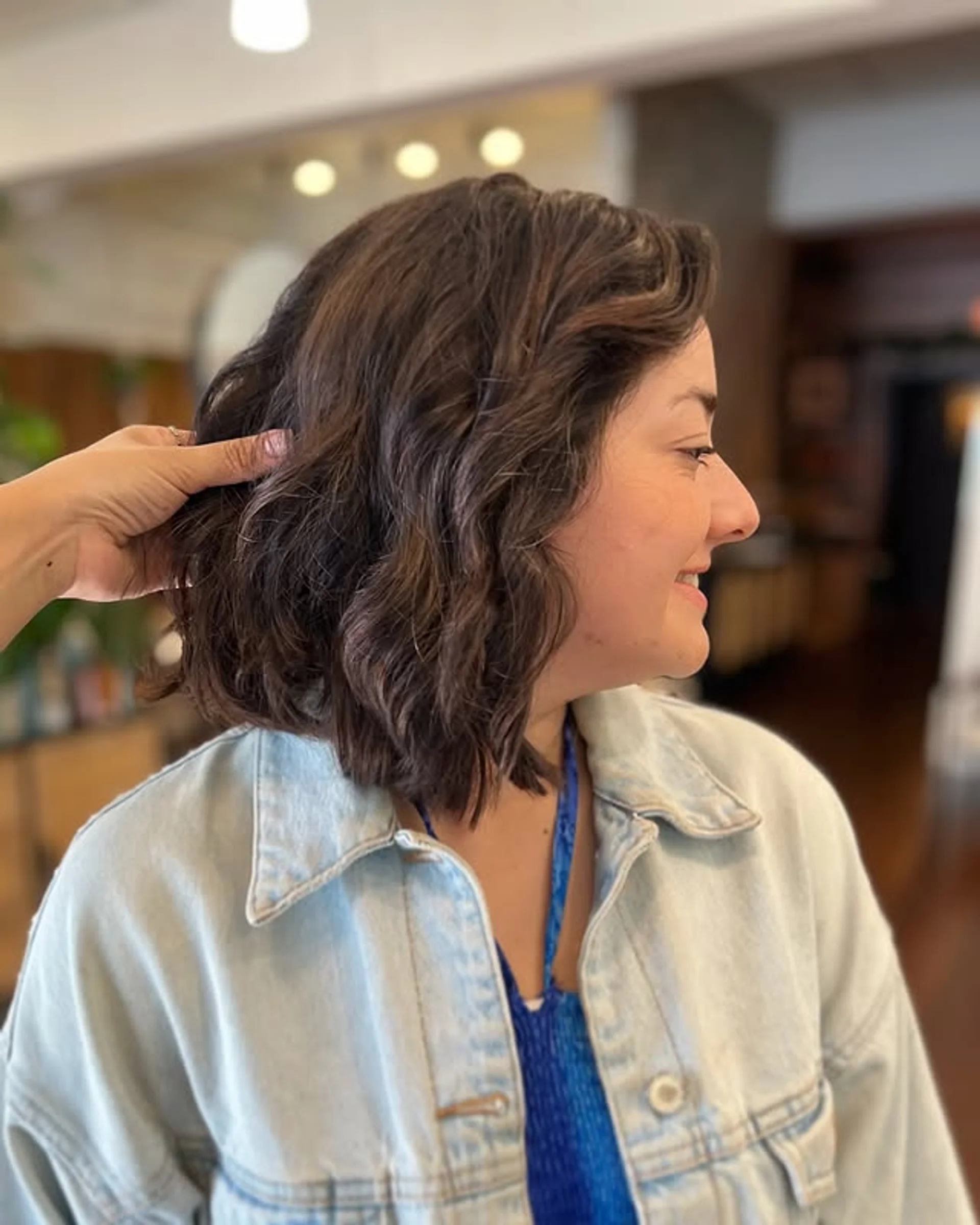 A short, voluminous bob haircut with a side part and soft, bouncy waves on dark hair. - Preview 2