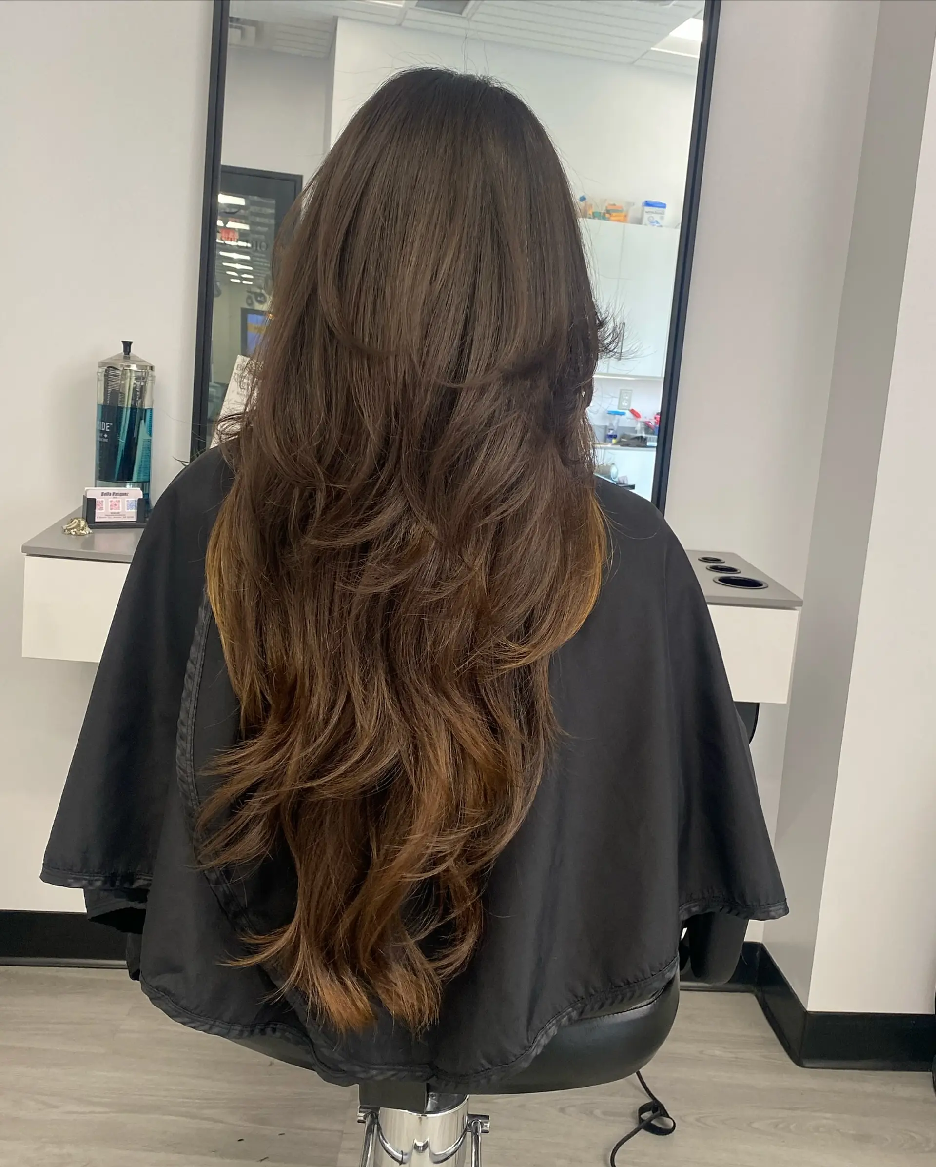 Very long brunette hair styled with voluminous cascading layers and soft, feathered blowout ends. 1