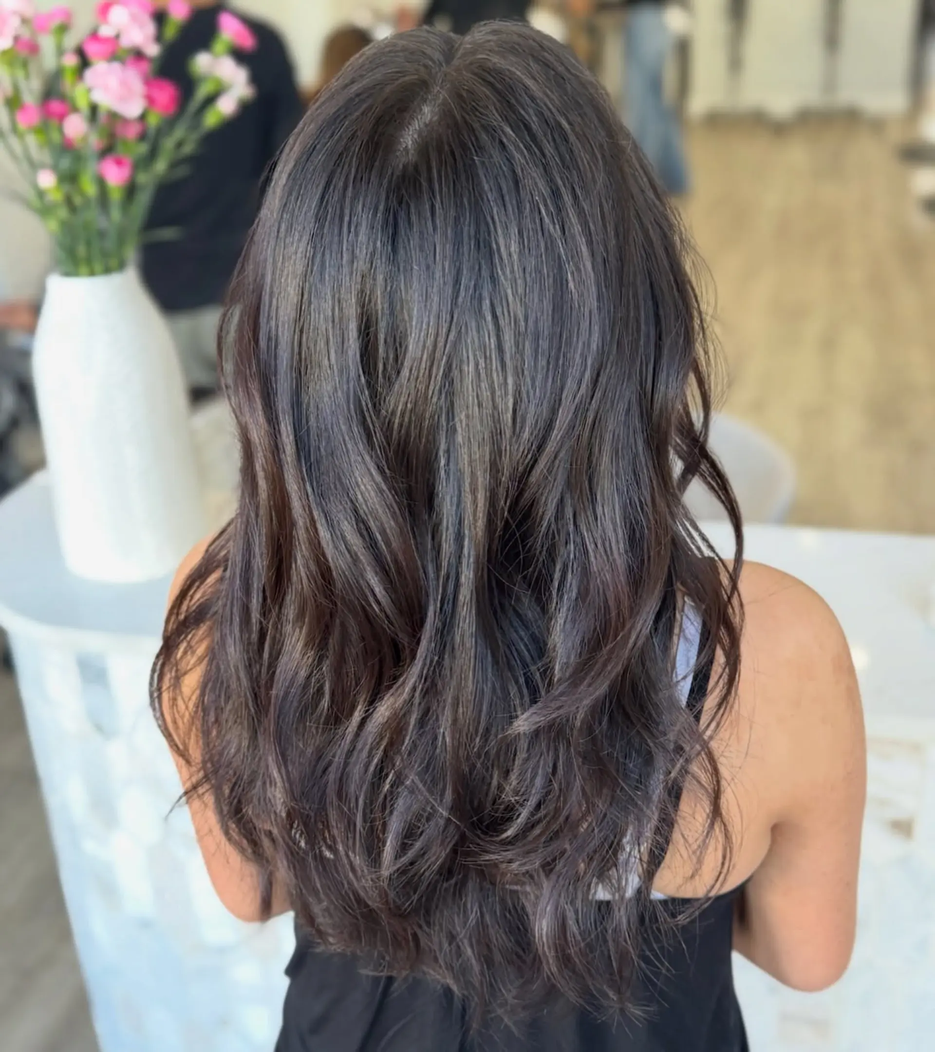 Long, rich dark brown hair cut with soft cascading layers and styled into loose, dimensional waves. 1