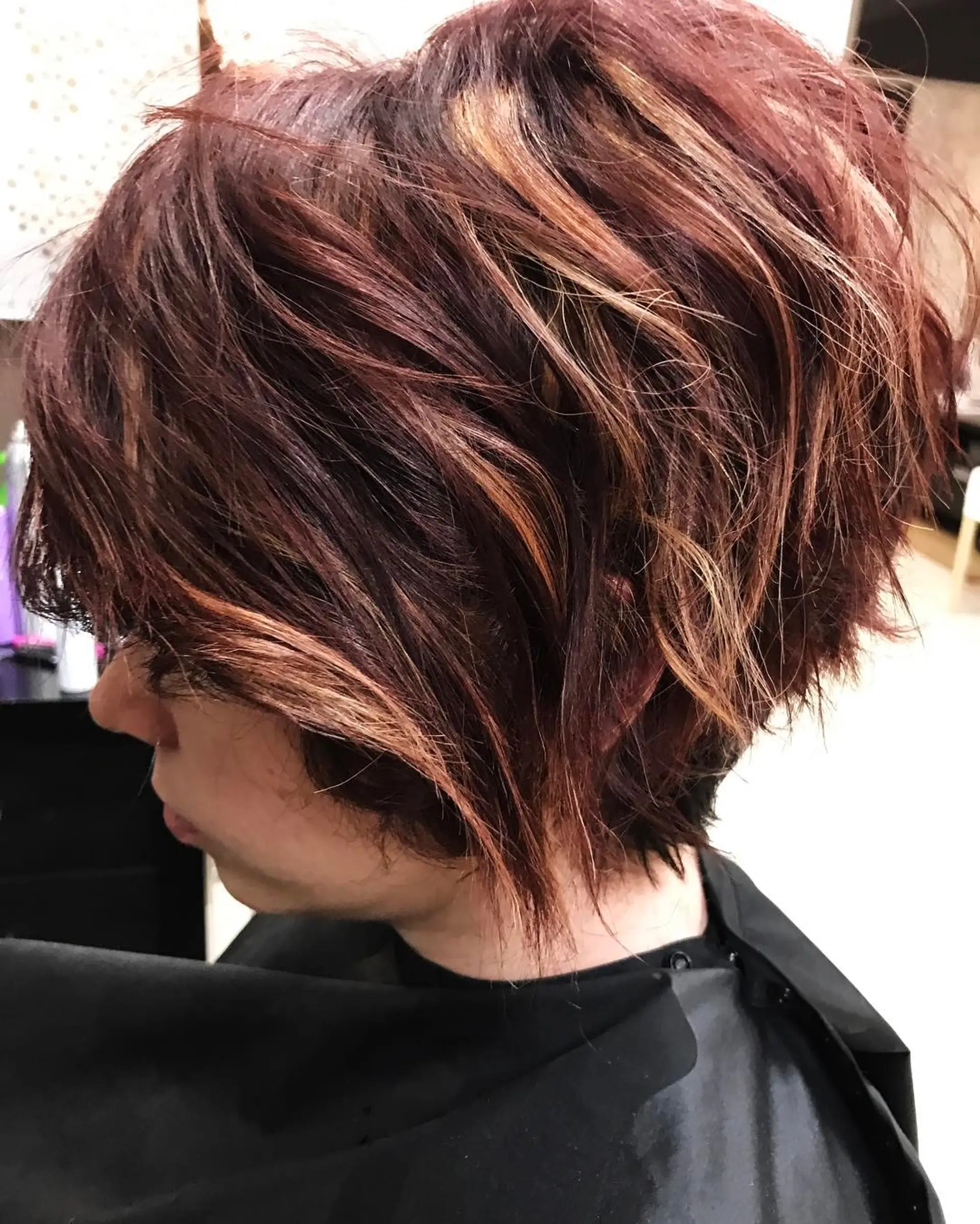 A textured short pixie bob featuring a rich auburn-red base enhanced with dimensional copper highlights. 1