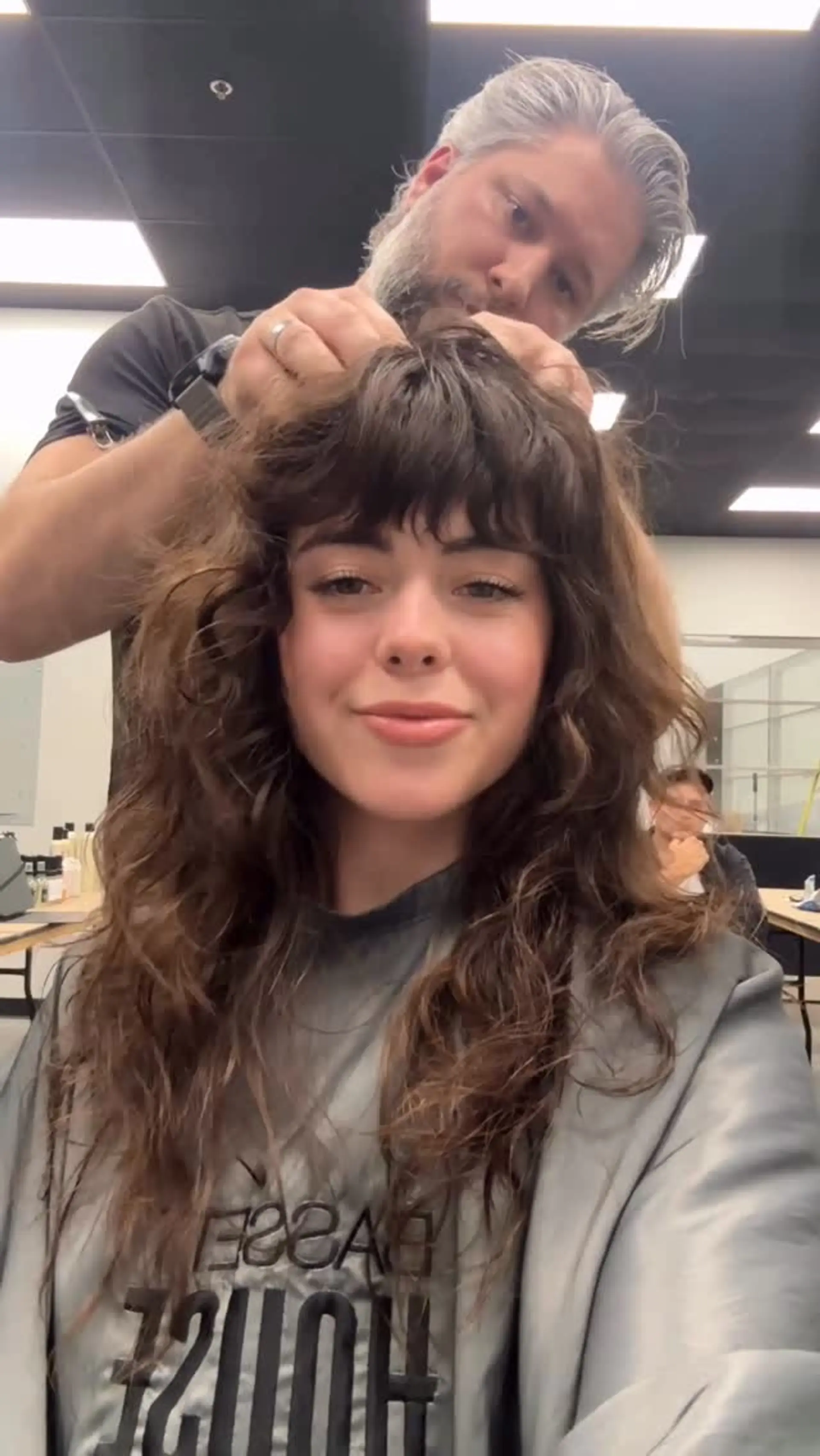 A layered curly shag haircut featuring textured, piecey bangs and soft face-framing volume throughout naturally wavy and curly locks. 1