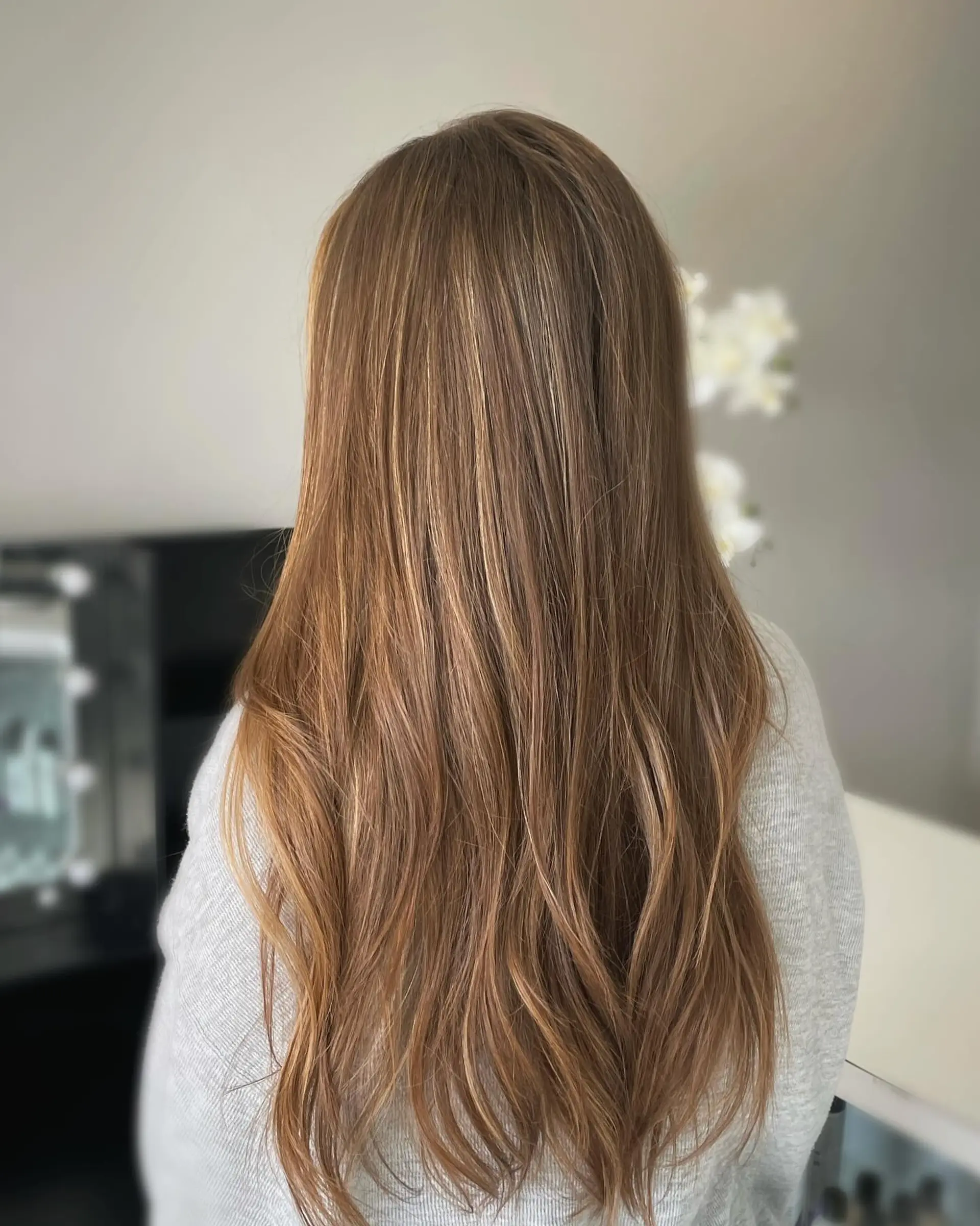 Long natural light brown hair accented with delicate, subtle highlights and soft waves at the ends. 1