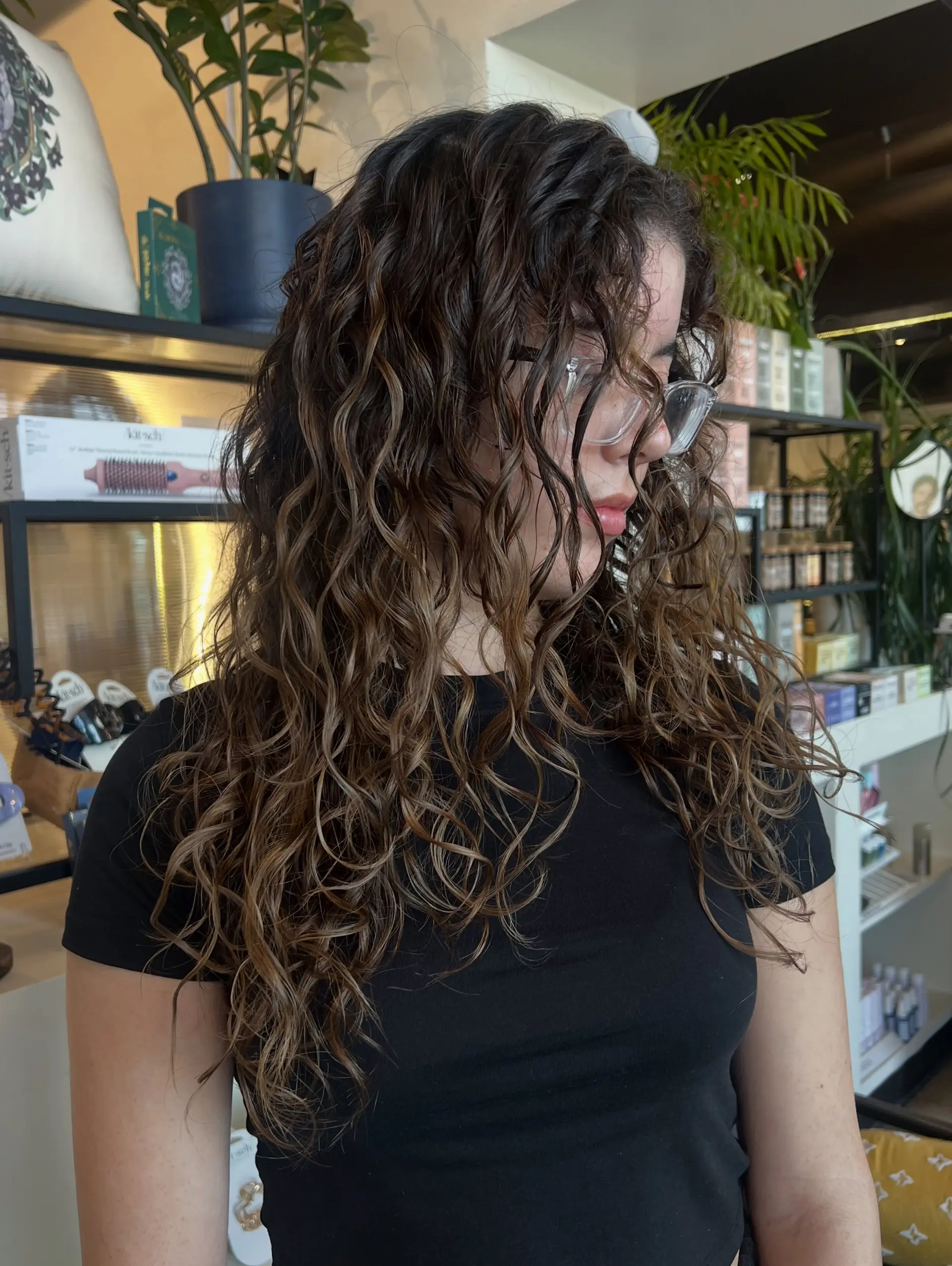 Long defined curly hair treated with a reverse balayage, blending rich dark brown depth with warm caramel ribbons. 1